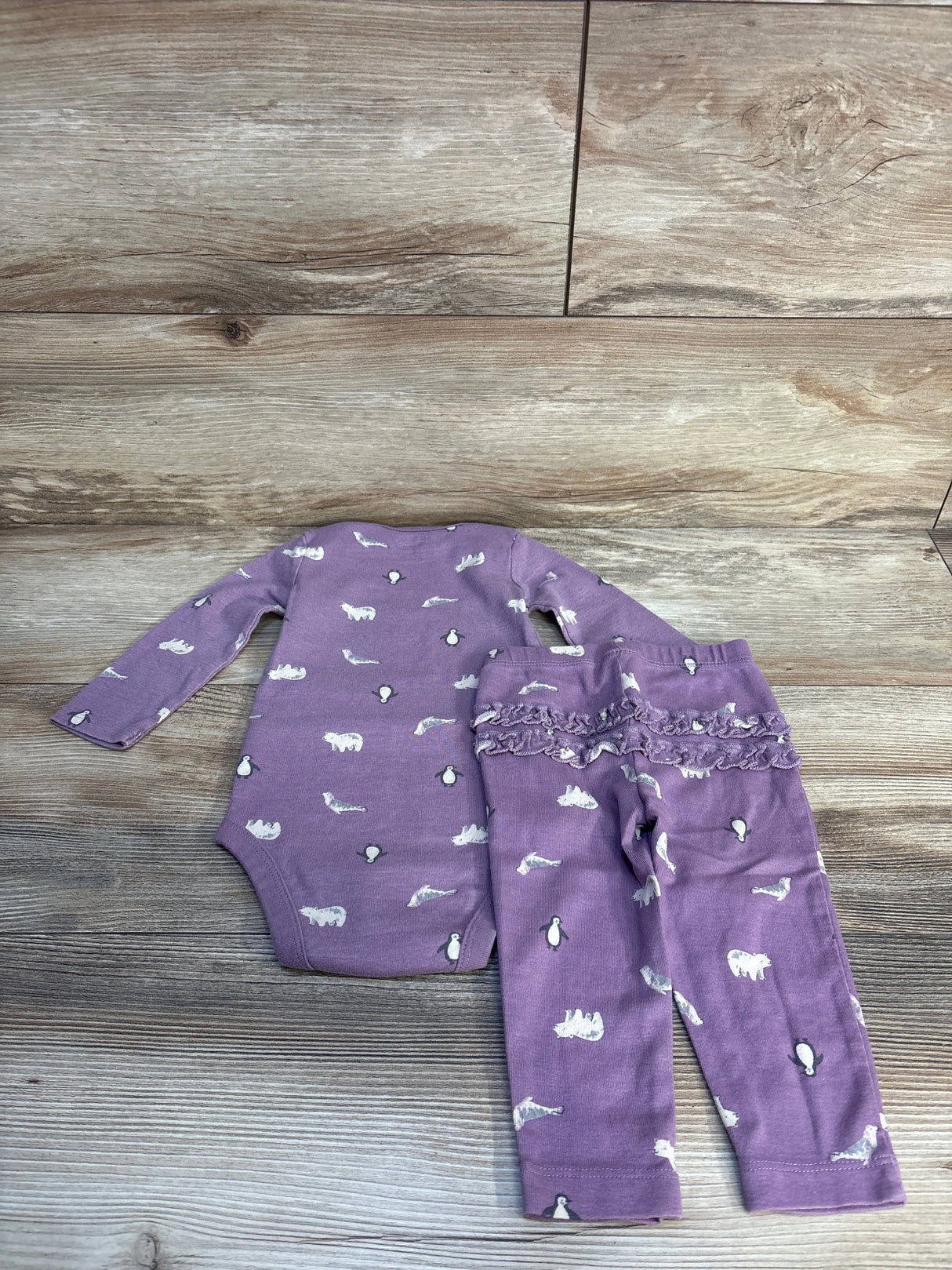 Purple baby outfit set with animal print, long sleeve bodysuit and ruffle pants on wood floor
