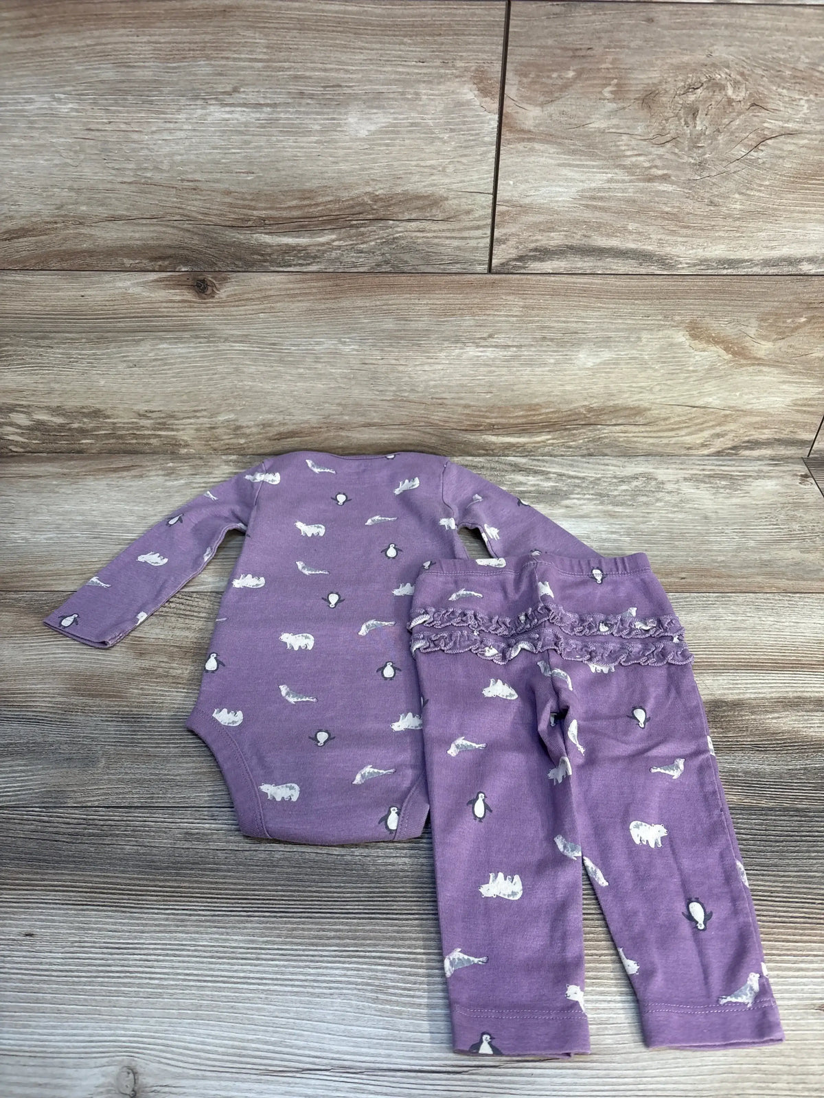 Purple baby outfit set with animal print, long sleeve bodysuit and ruffle pants on wood floor