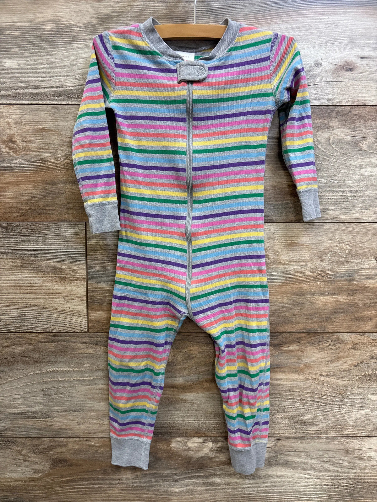 Front view of Hanna Andersson footless sleeper in size 3T with multicolor stripes, grey trim, and front zipper on wood background