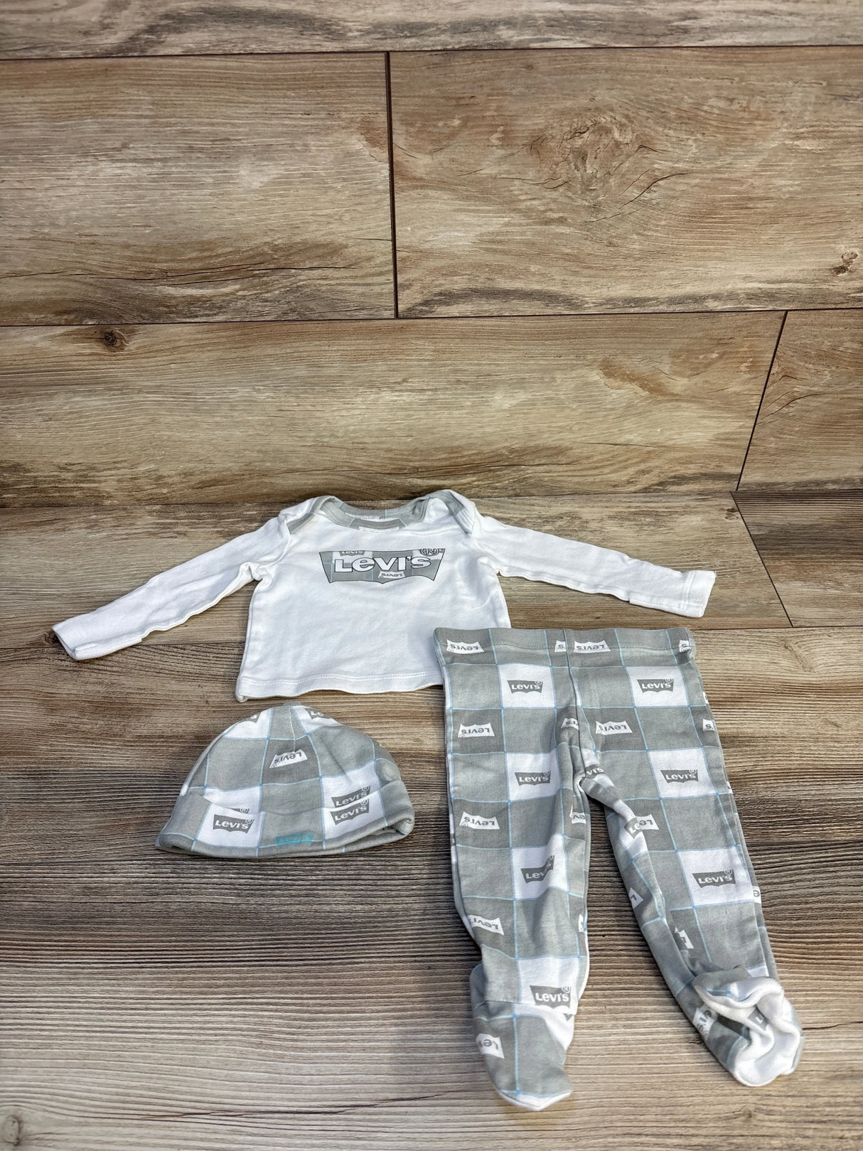 Levi's baby outfit set with long sleeve shirt, gray checkered pants, and matching hat on wood floor