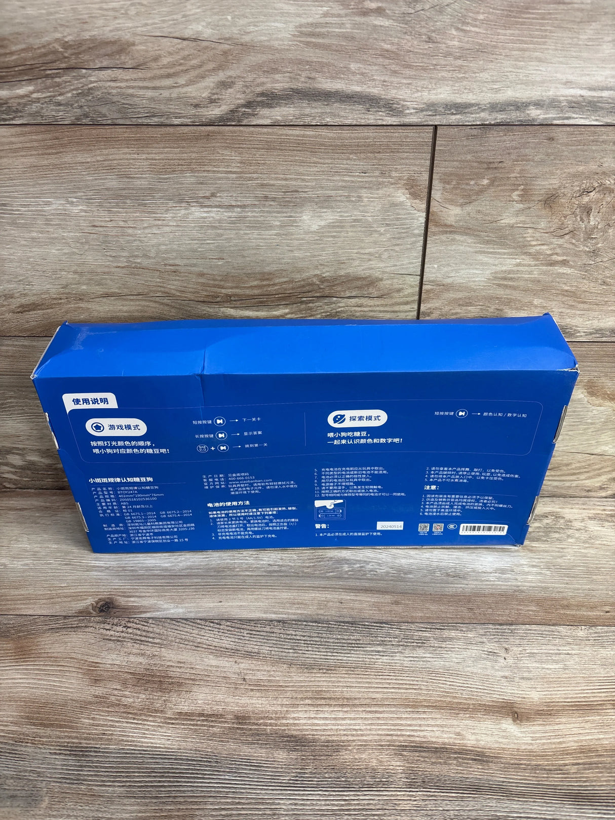 Rear view of BanBan's Candy Dog color-sorting toy box showcasing printed Chinese instructions and light edge wear on blue packaging on wood floor