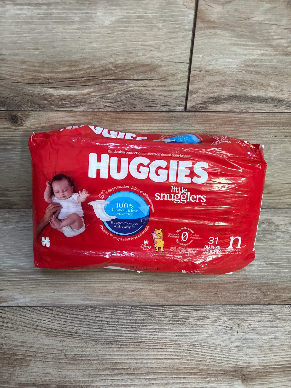 Huggies Little Snugglers newborn diapers pack, red packaging on wood floor