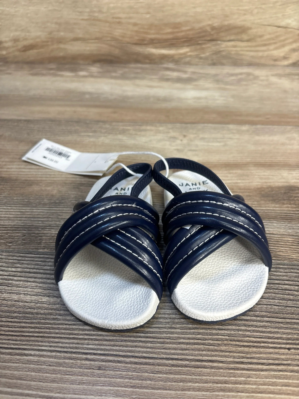Navy blue and white baby sandals with crisscross straps on wooden background