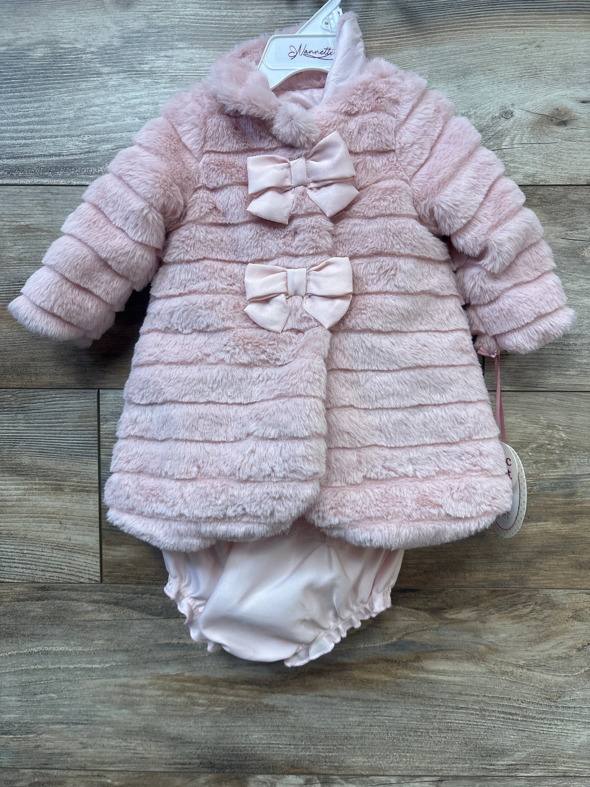 Front view of Nannette 3-piece tulle dress, faux-fur coat, and bloomers set showcasing pink coat with bows on wood background