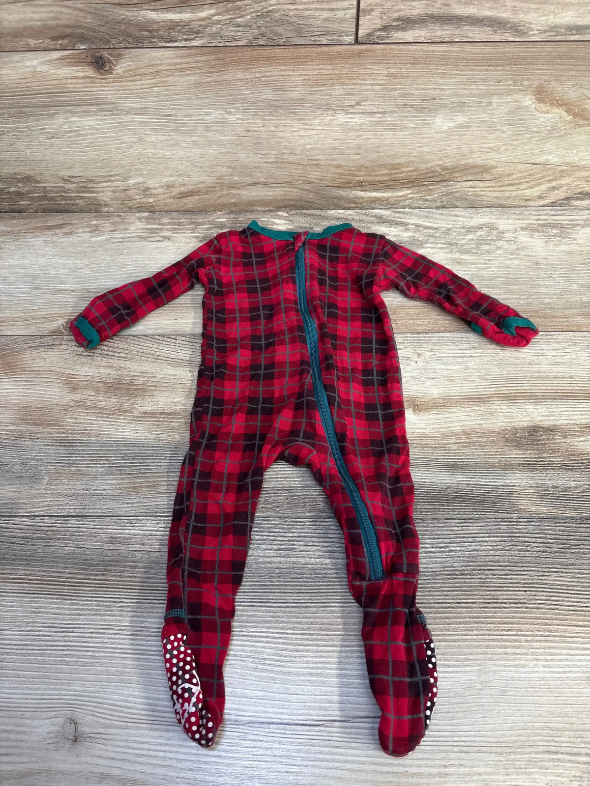 Flat lay of Kickee Pants zippered footie in red plaid with teal zipper and dotted non slip soles on wood background