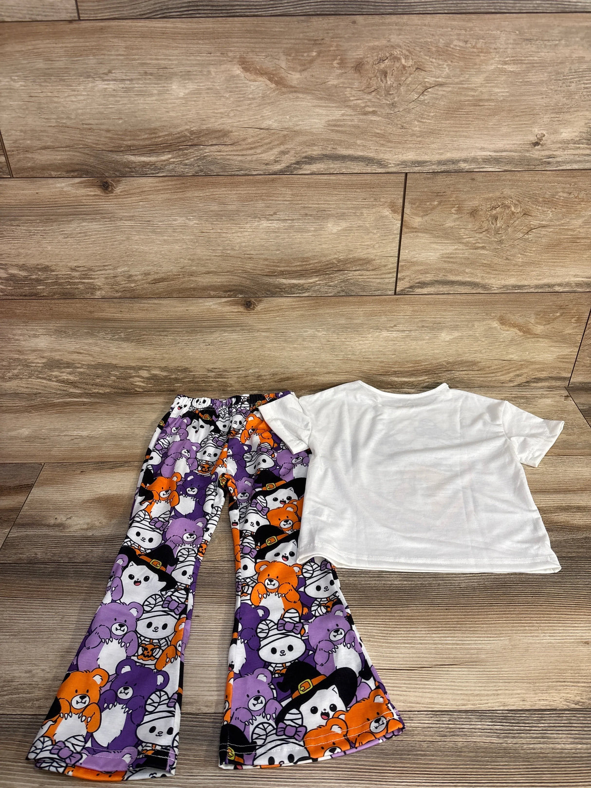 Halloween-themed kids' outfit with purple, orange, and white bear print pants and a white tee.