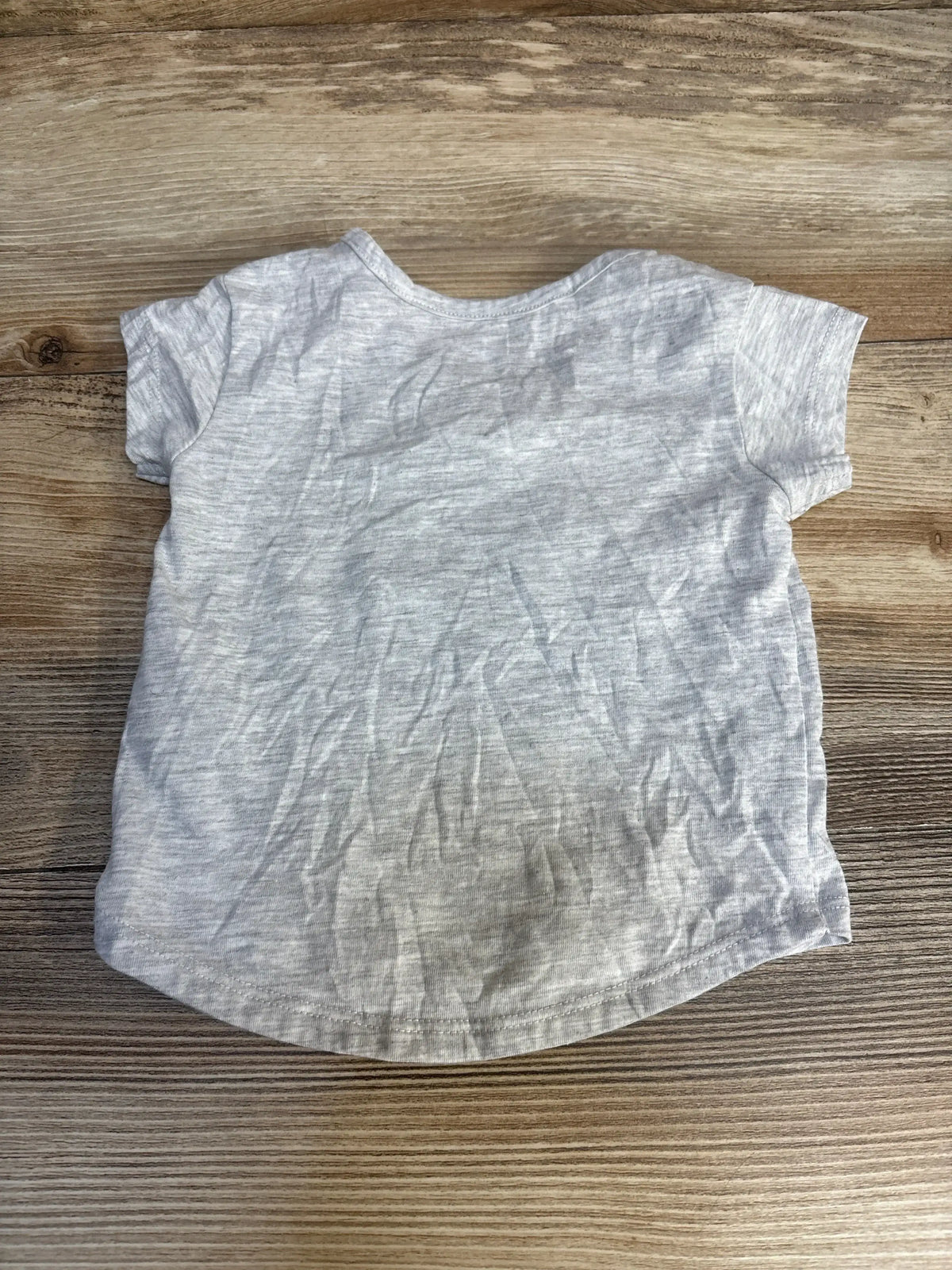 Back view of Adidas toddler t-shirt (3-6M) showing heather gray fabric, short sleeves, curved hem on wood background