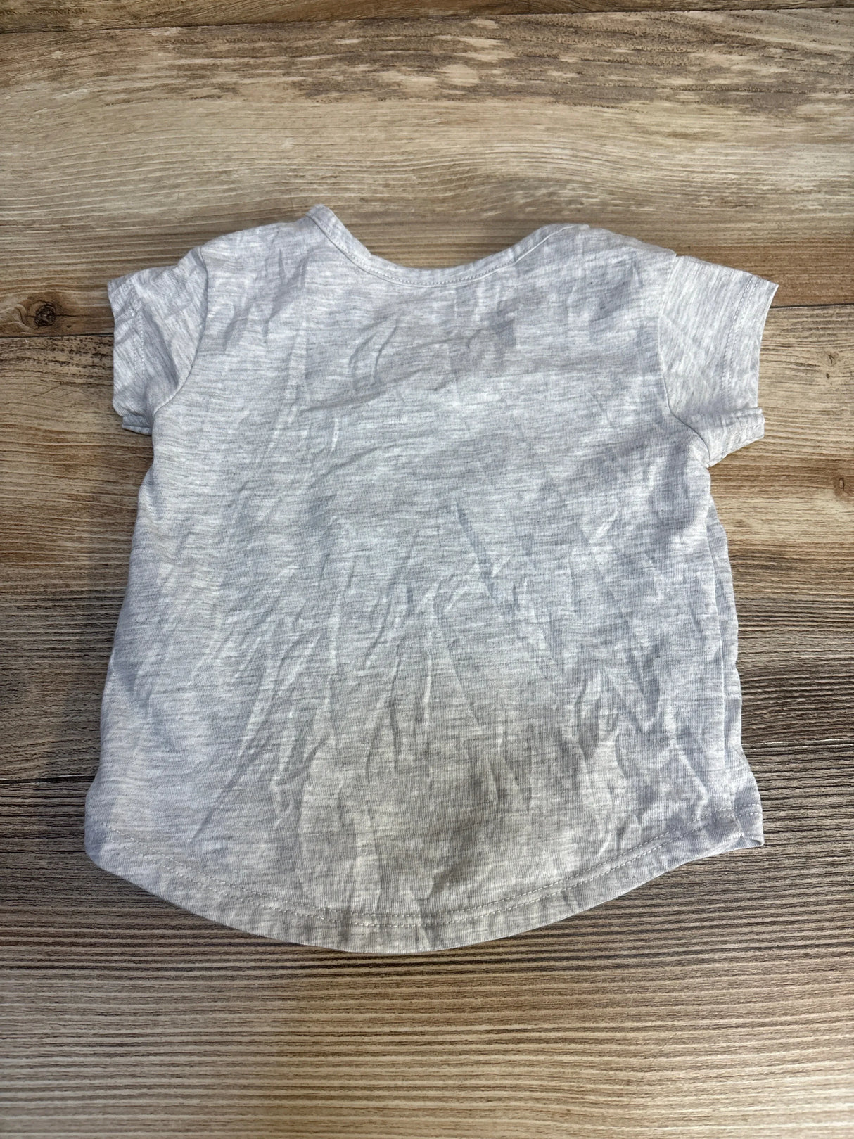 Light gray short sleeve toddler t-shirt laid flat on wooden surface