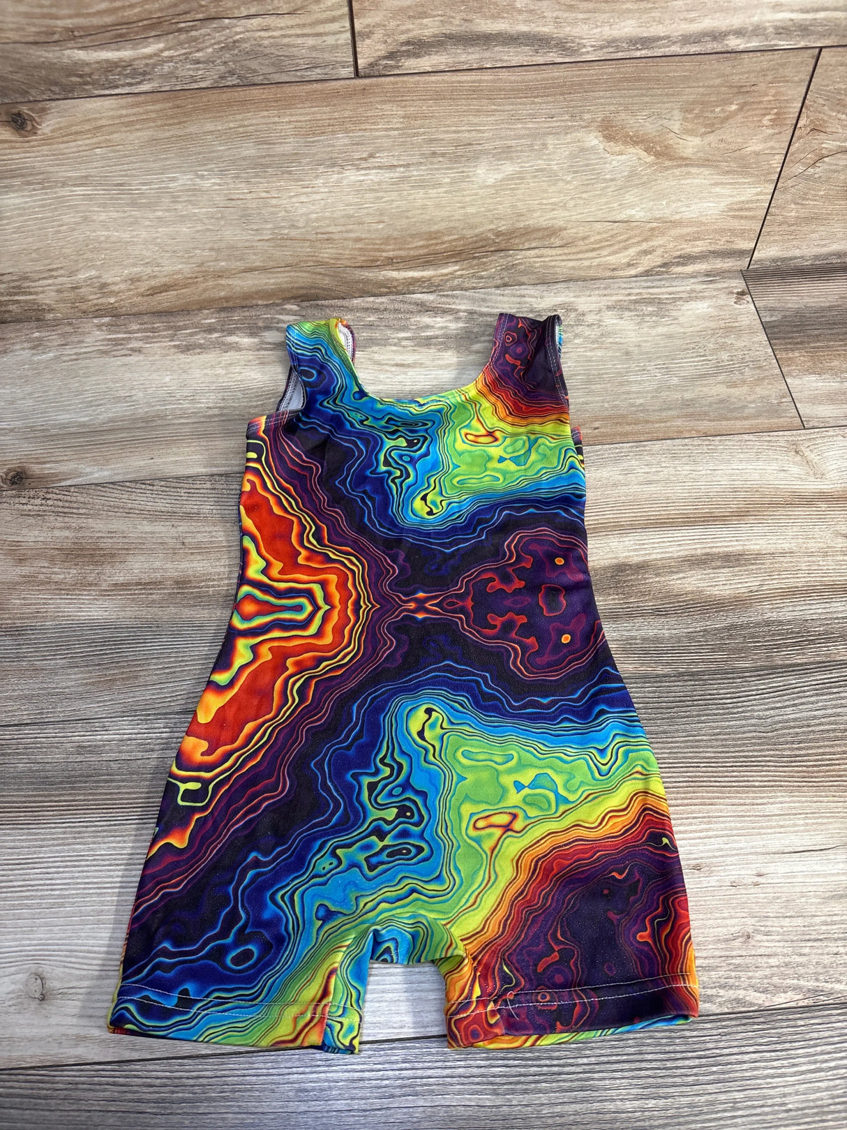 Colorful abstract pattern romper on wood floor, vibrant baby outfit