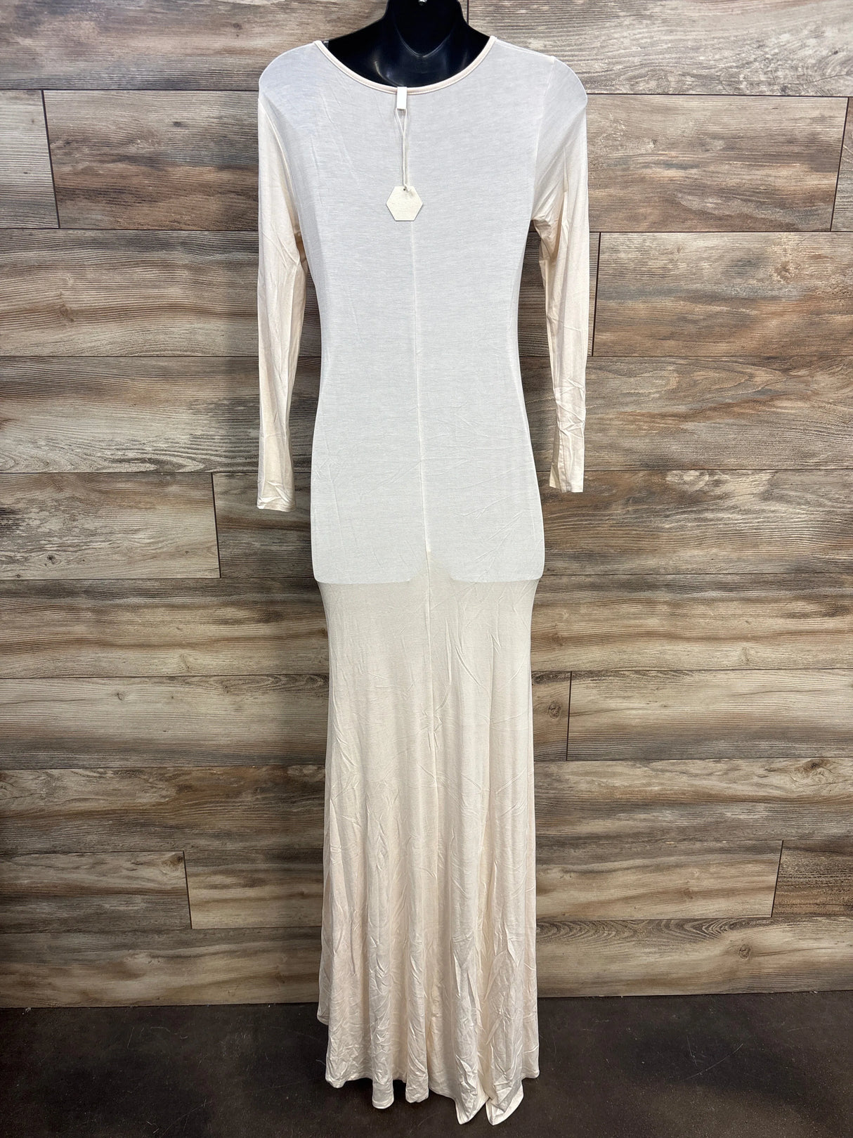 Long sleeve cream maxi dress on black mannequin against rustic wood wall background