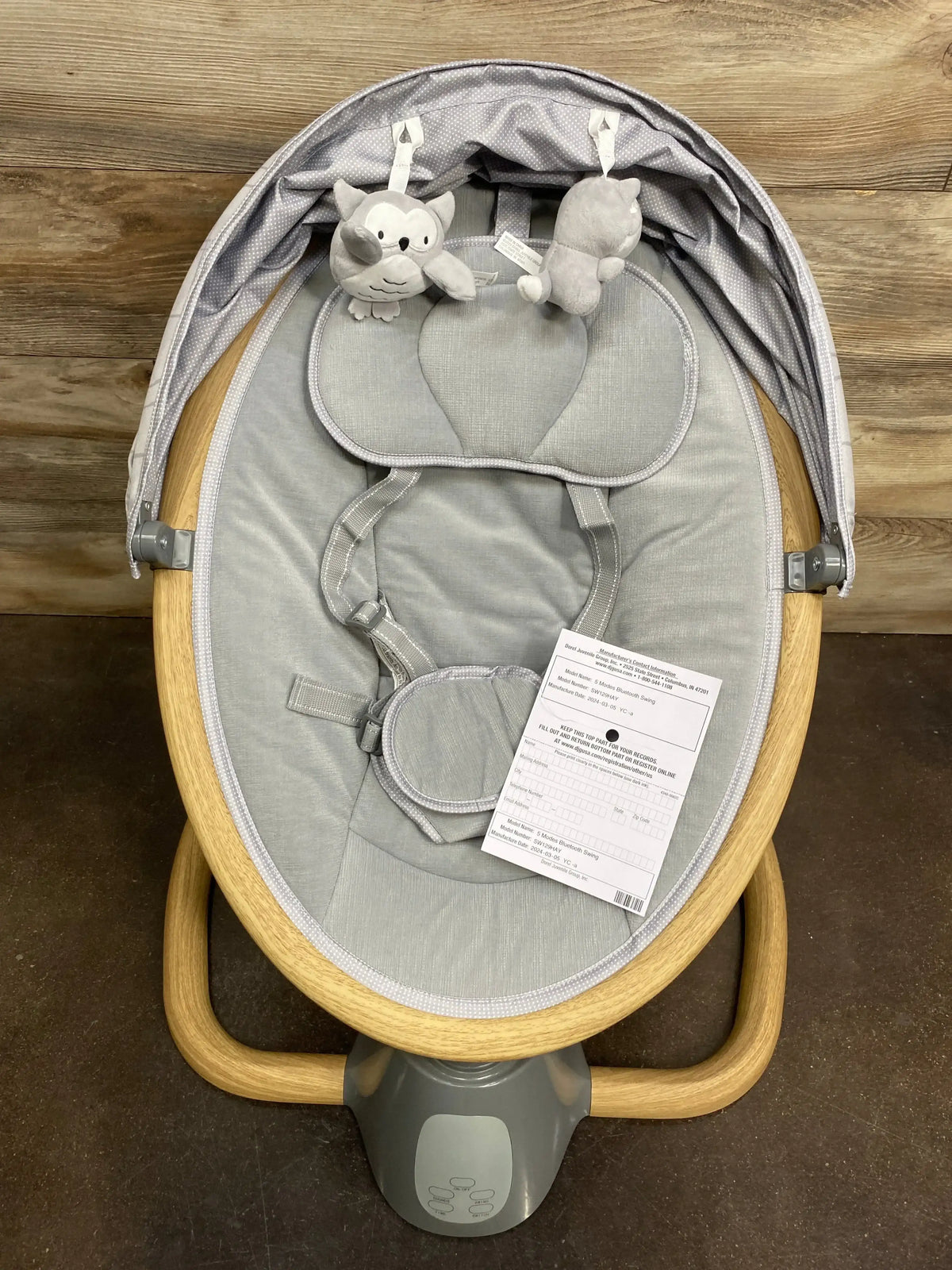 Top-down view of Safety 1st 5-Modes Bluetooth baby swing with gray seat, wooden oval frame, harness, and toy bar