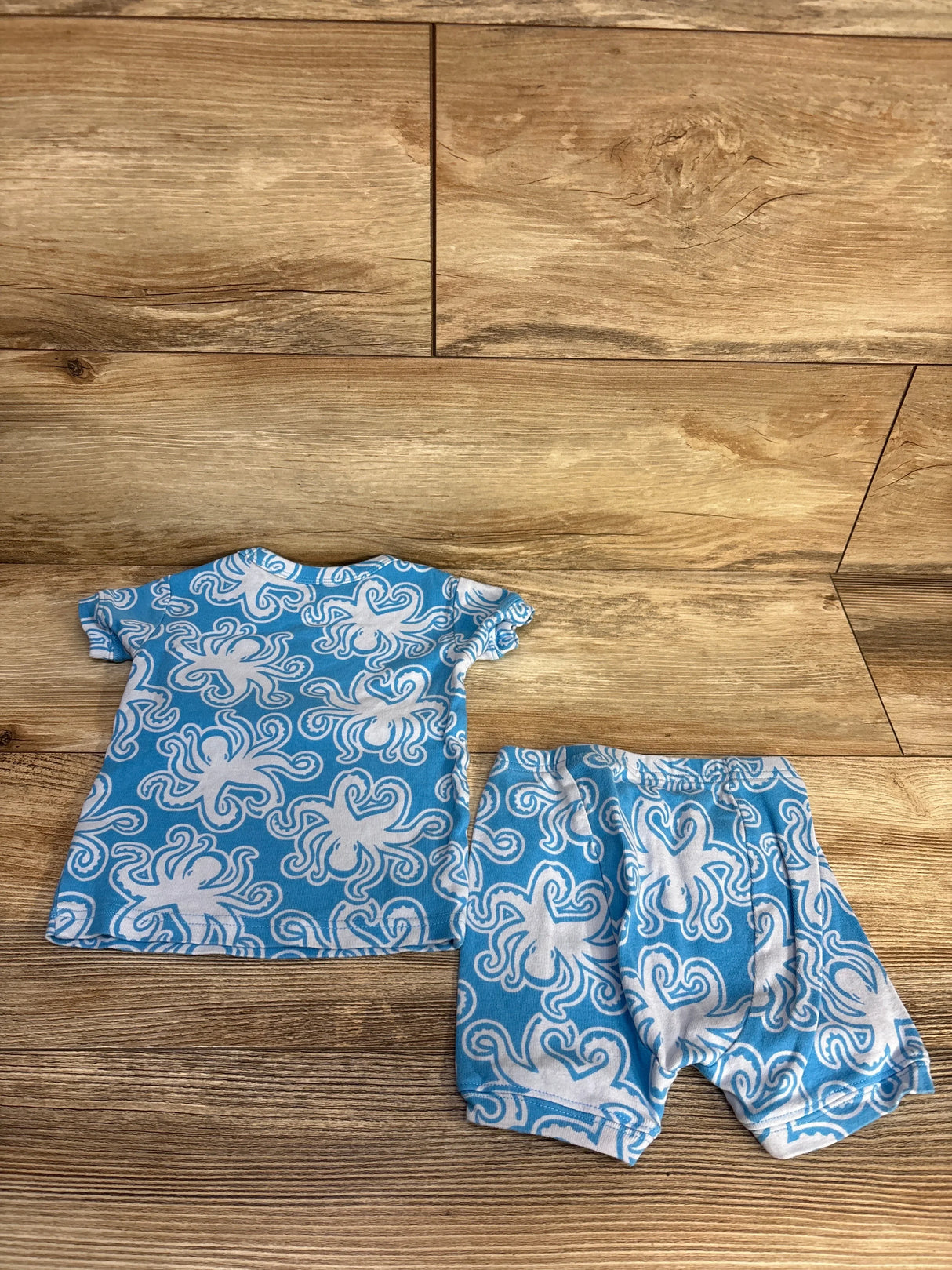 Blue baby outfit set with white octopus pattern, short-sleeve top and matching shorts on wood floor