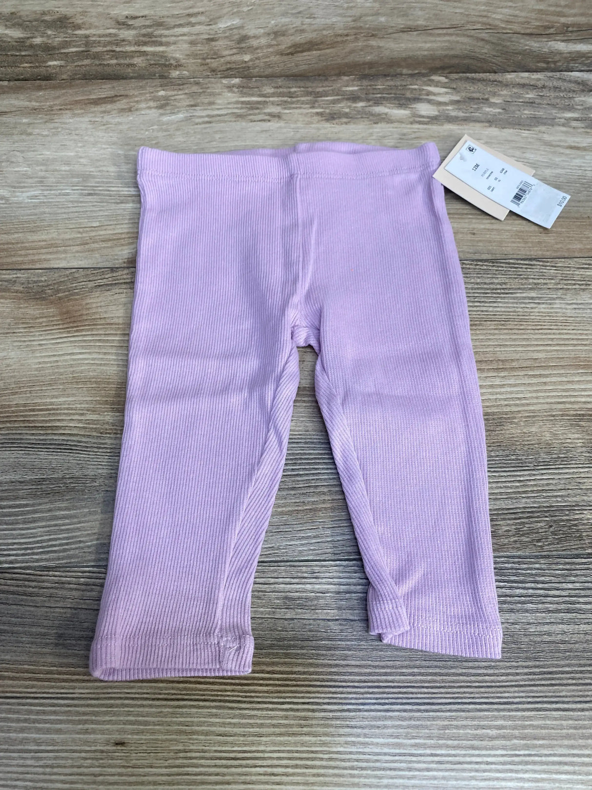 Front view of Grayson mini ribbed baby leggings, purple, showing ribbed texture, elastic waist, and 12m tag on wood