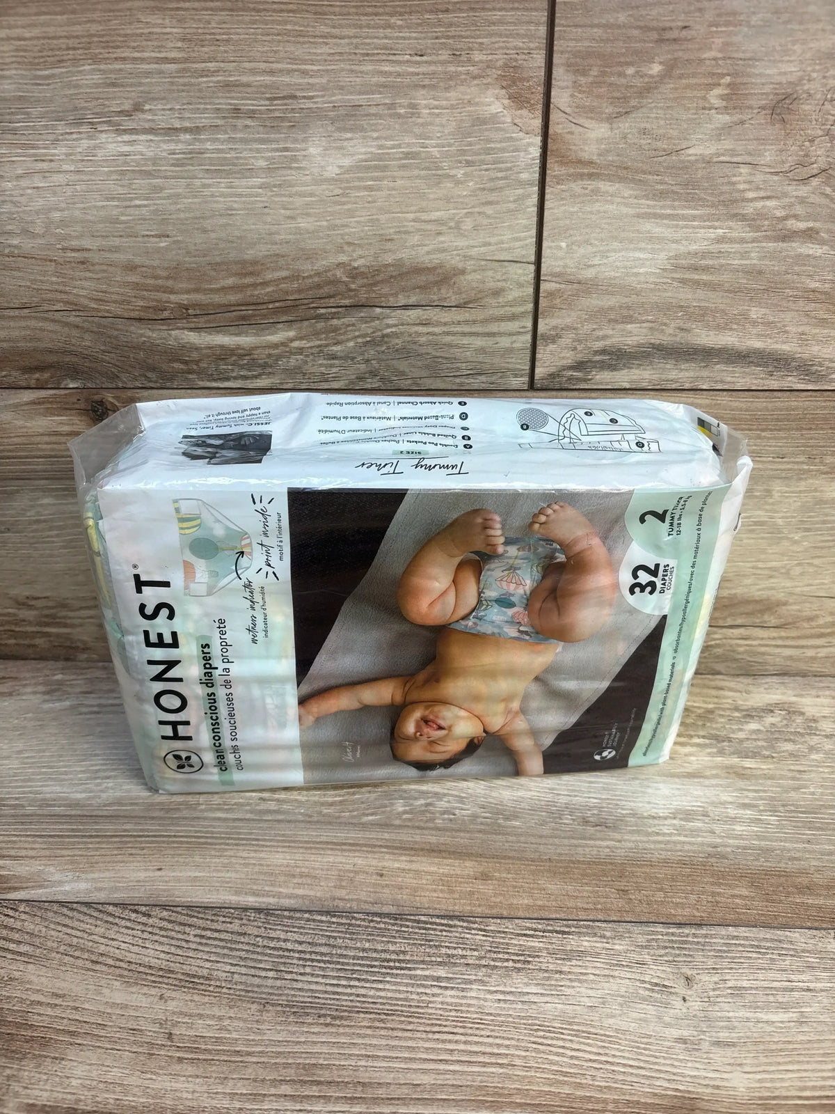 Pack of Honest brand size 2 diapers with baby image, on wood surface