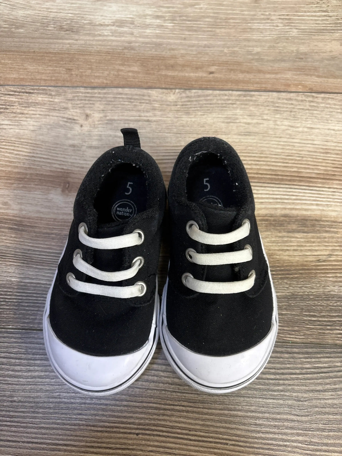 Front three-quarter view of Wonder Nation toddler black canvas bump-toe sneakers showing rubber toe bumper and white sole
