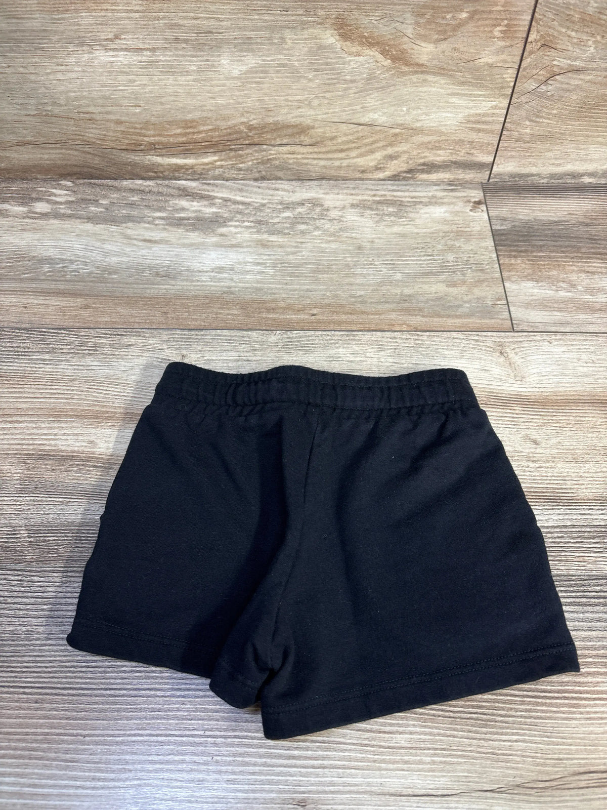 Front view of black Cat & Jack knit shorts showcasing elastic waistband and stitched hems on a wood-look floor