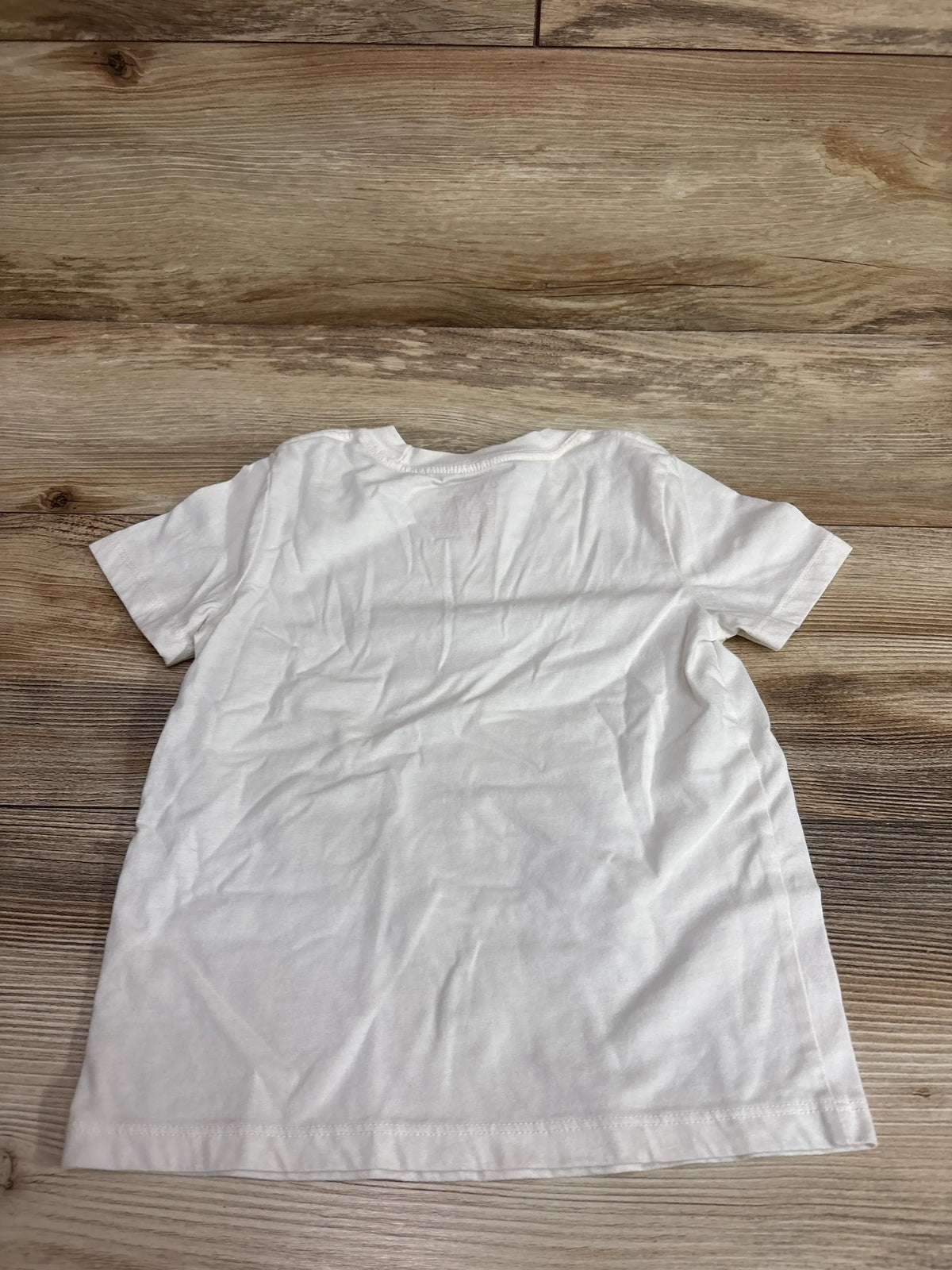 Back view of a Cat & Jack ivory seashell shirt in size 4T on a wooden surface.