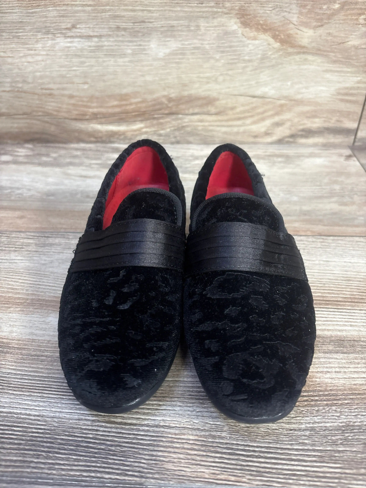 Front view of Bruno Marc black tuxedo dress loafers showcasing slip-on bands and red lining on a wood floor