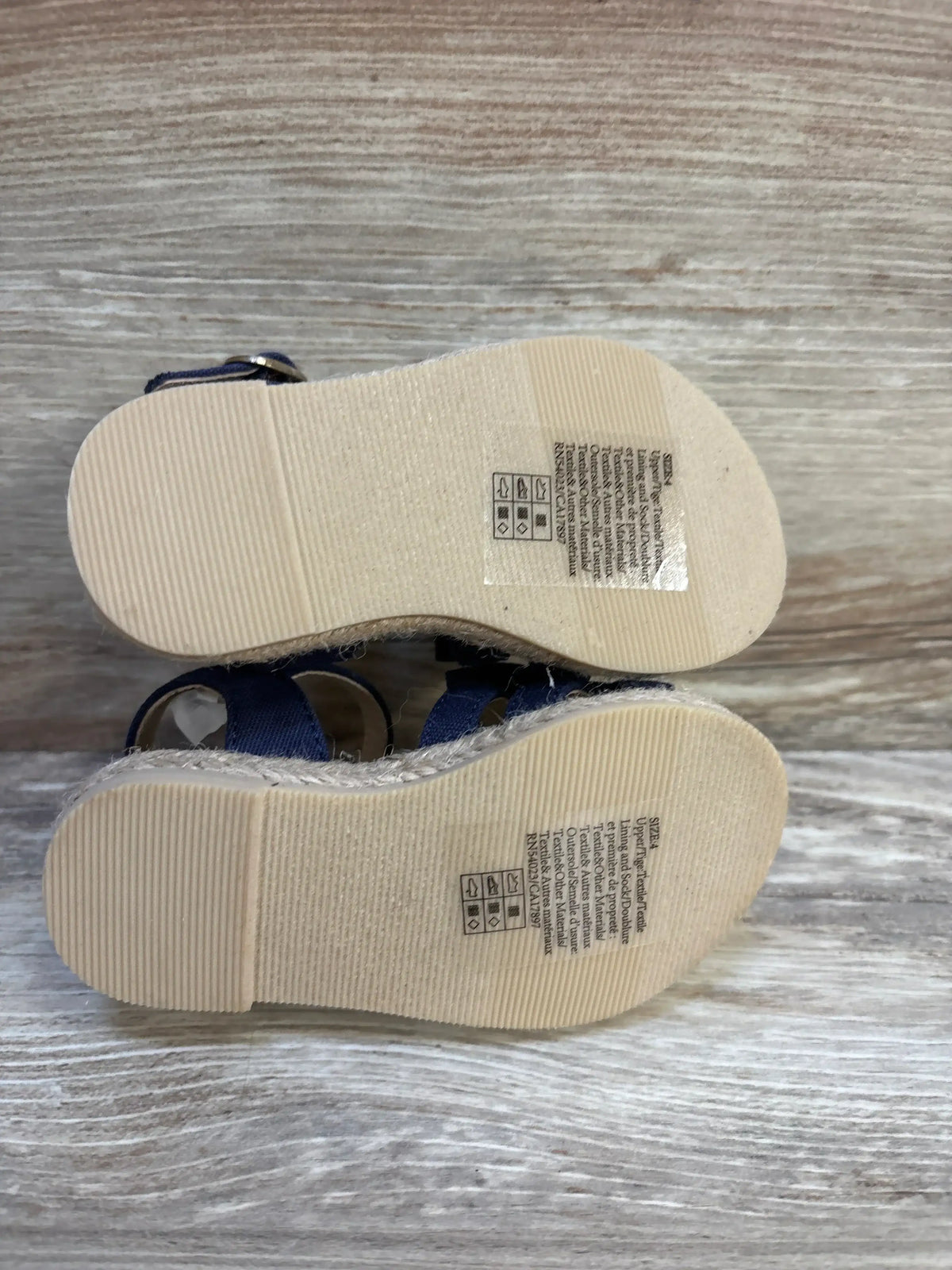 Bottom view of toddler blue sandals with textured rubber soles and care label stickers