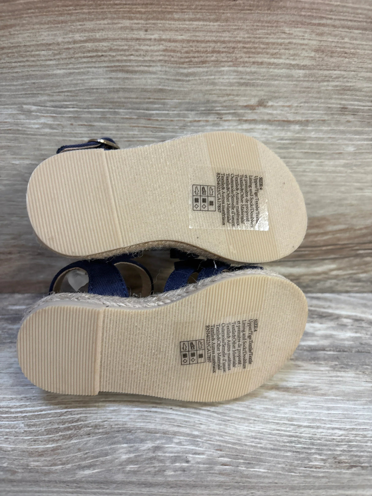 Bottom view of toddler blue sandals with textured rubber soles and care label stickers