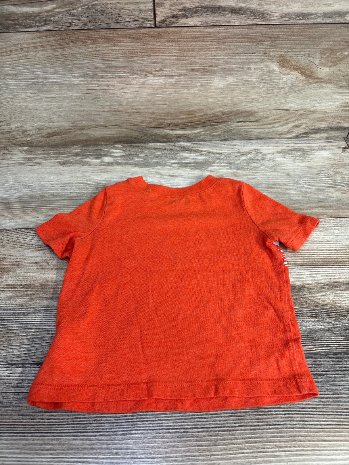 Bright orange short sleeve toddler t-shirt on wooden background