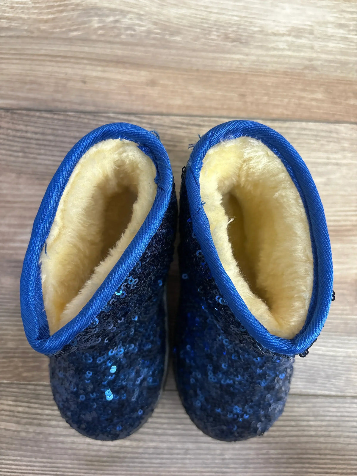 Blue sequin toddler boots with fuzzy lining on wooden floor