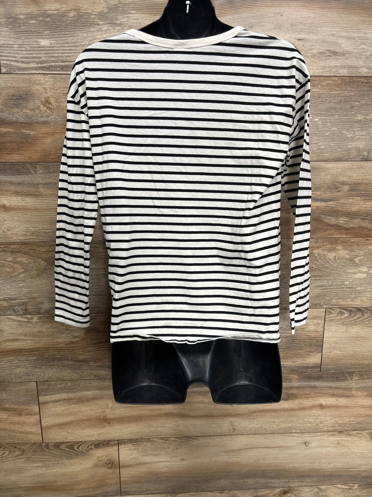 Black and white striped long sleeve shirt for kids on mannequin, wood background