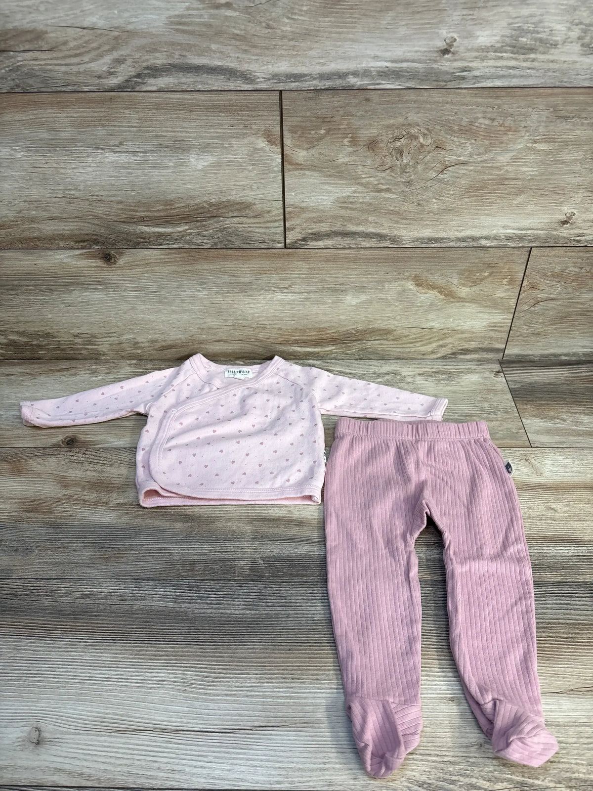 Top-down view of Rabbit and Bear 2pc heart print kimono top and footed pants set in pink, size 6-9m, on wood