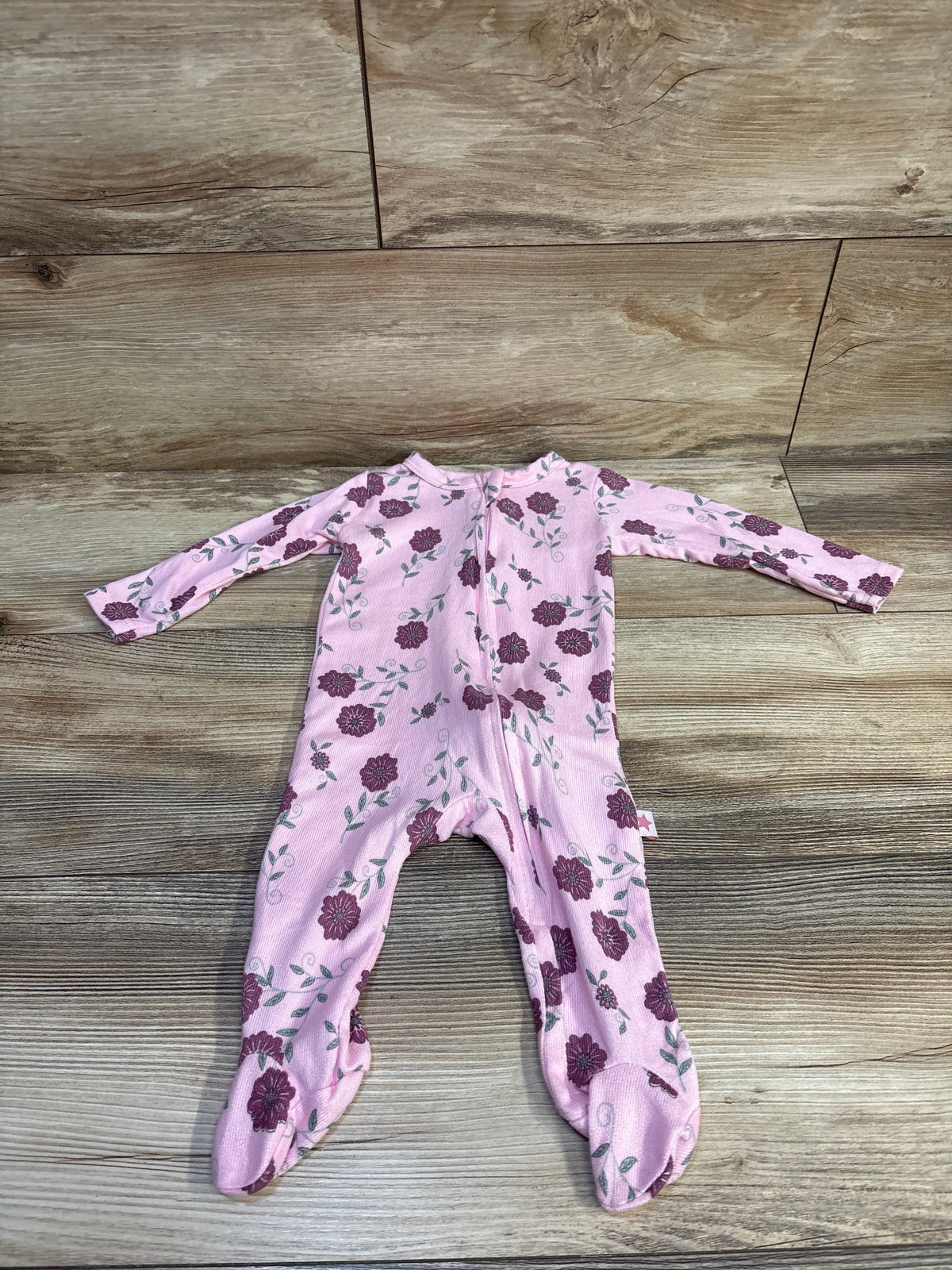 Flat lay of Millie & Myles pink floral footed baby sleeper showing back zipper and long sleeves on wood plank background