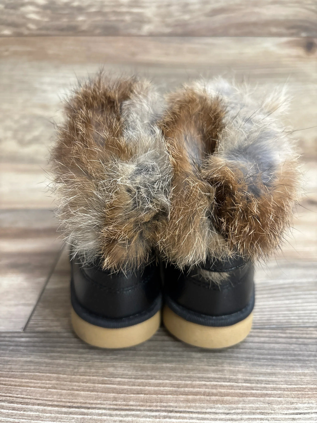 Back view of toddler faux fur lined black boots on wood floor