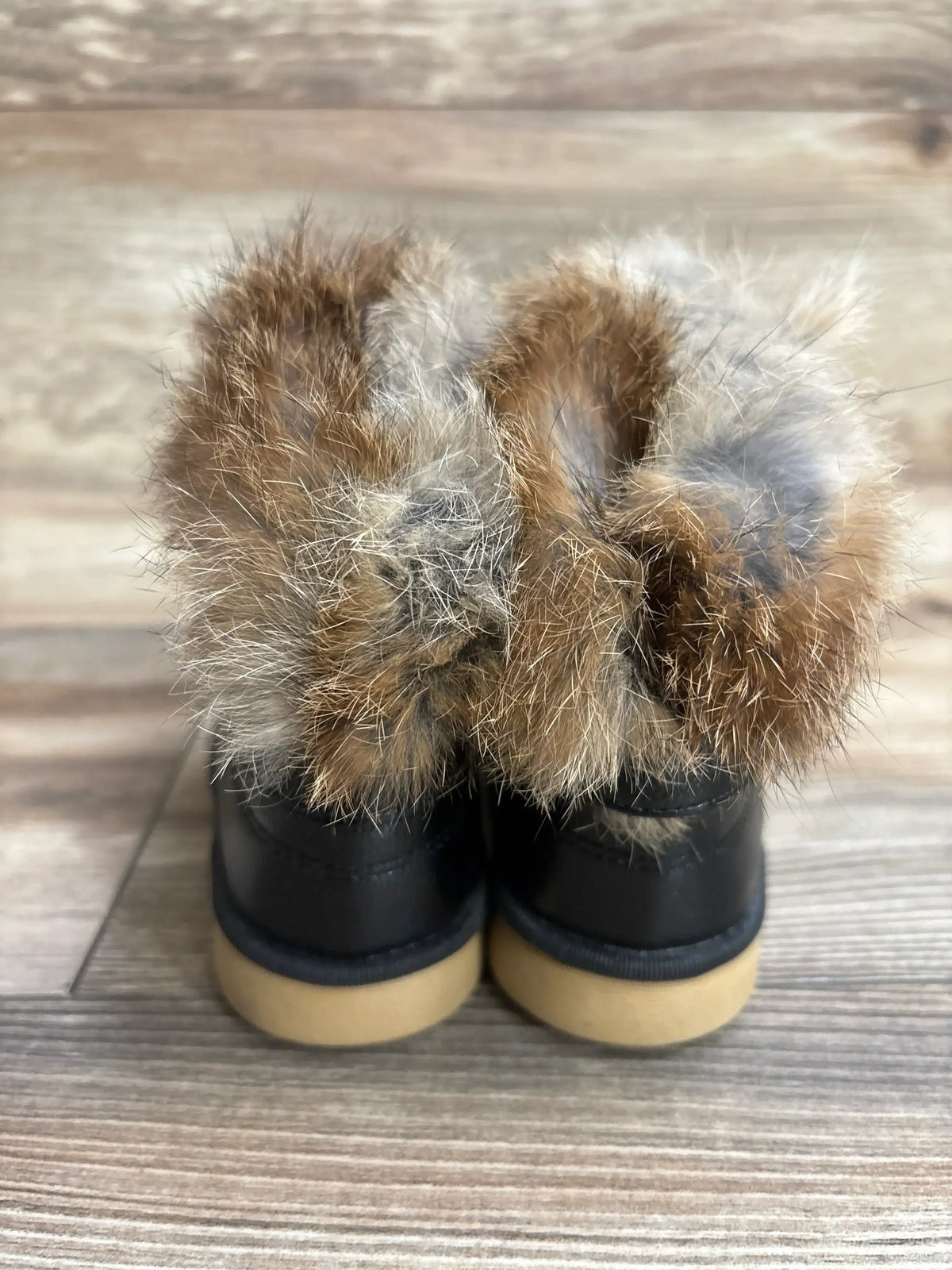 Back view of toddler faux fur lined black boots on wood floor