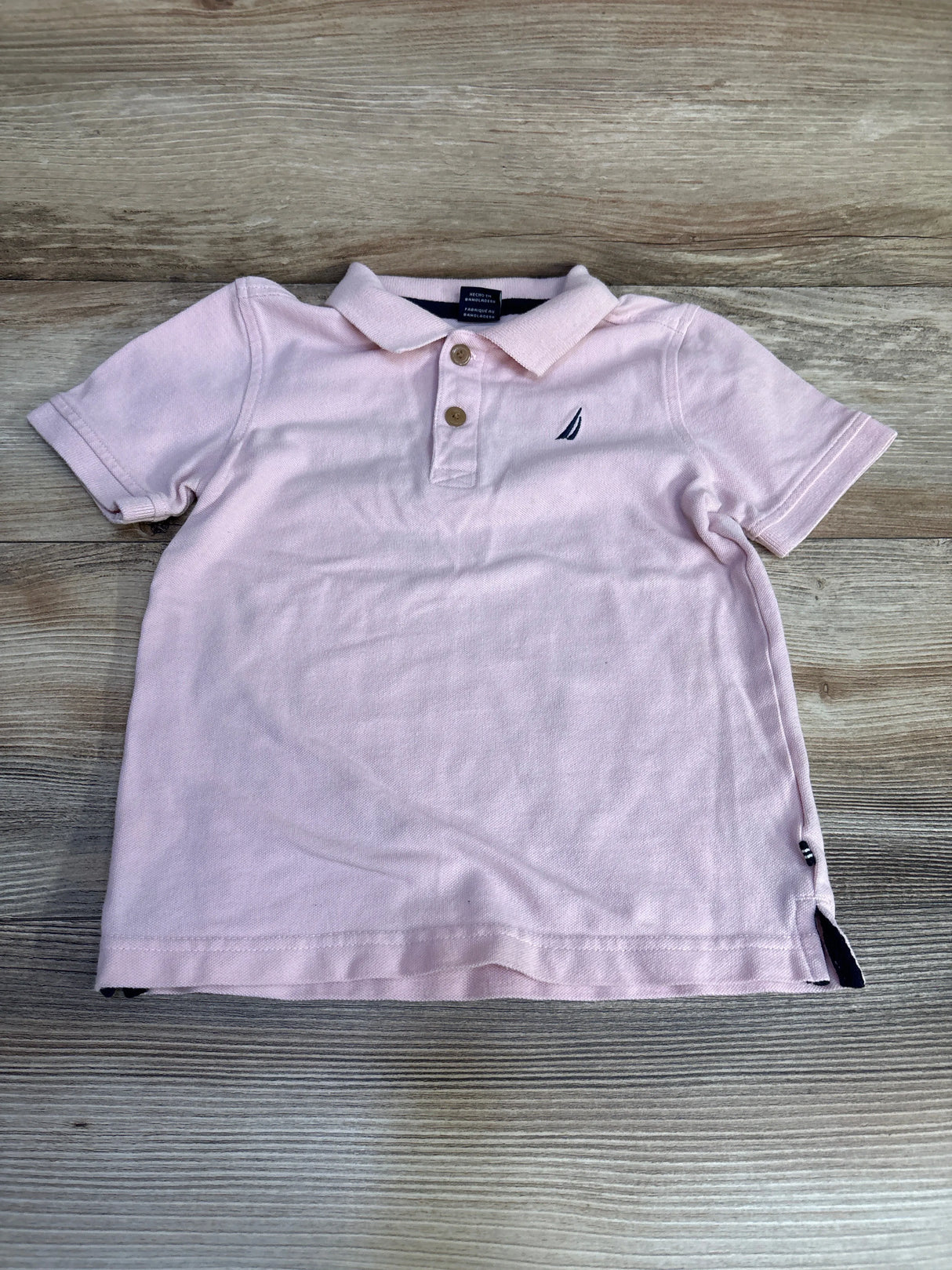 Light pink short sleeve polo shirt with buttons, wooden floor background