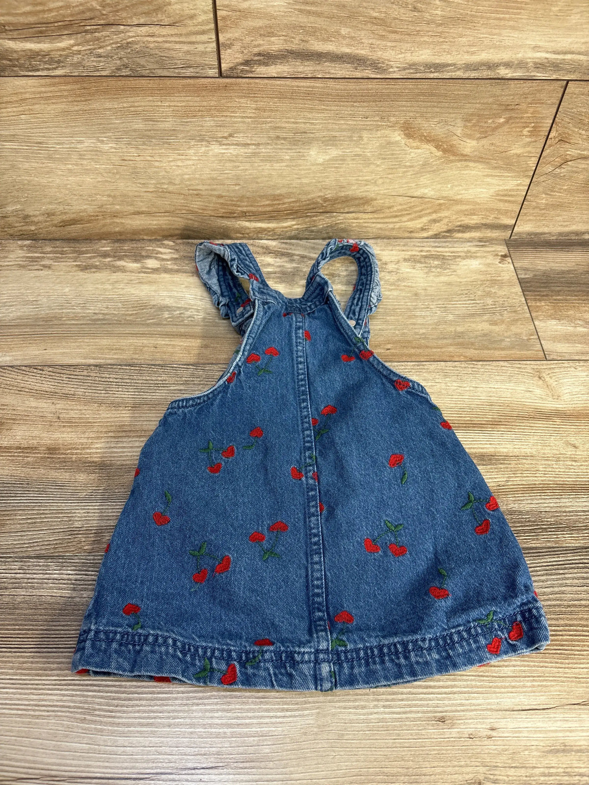 Front view of Isaac Mizrahi blue denim skirtall showcasing red floral embroidery on a wood floor