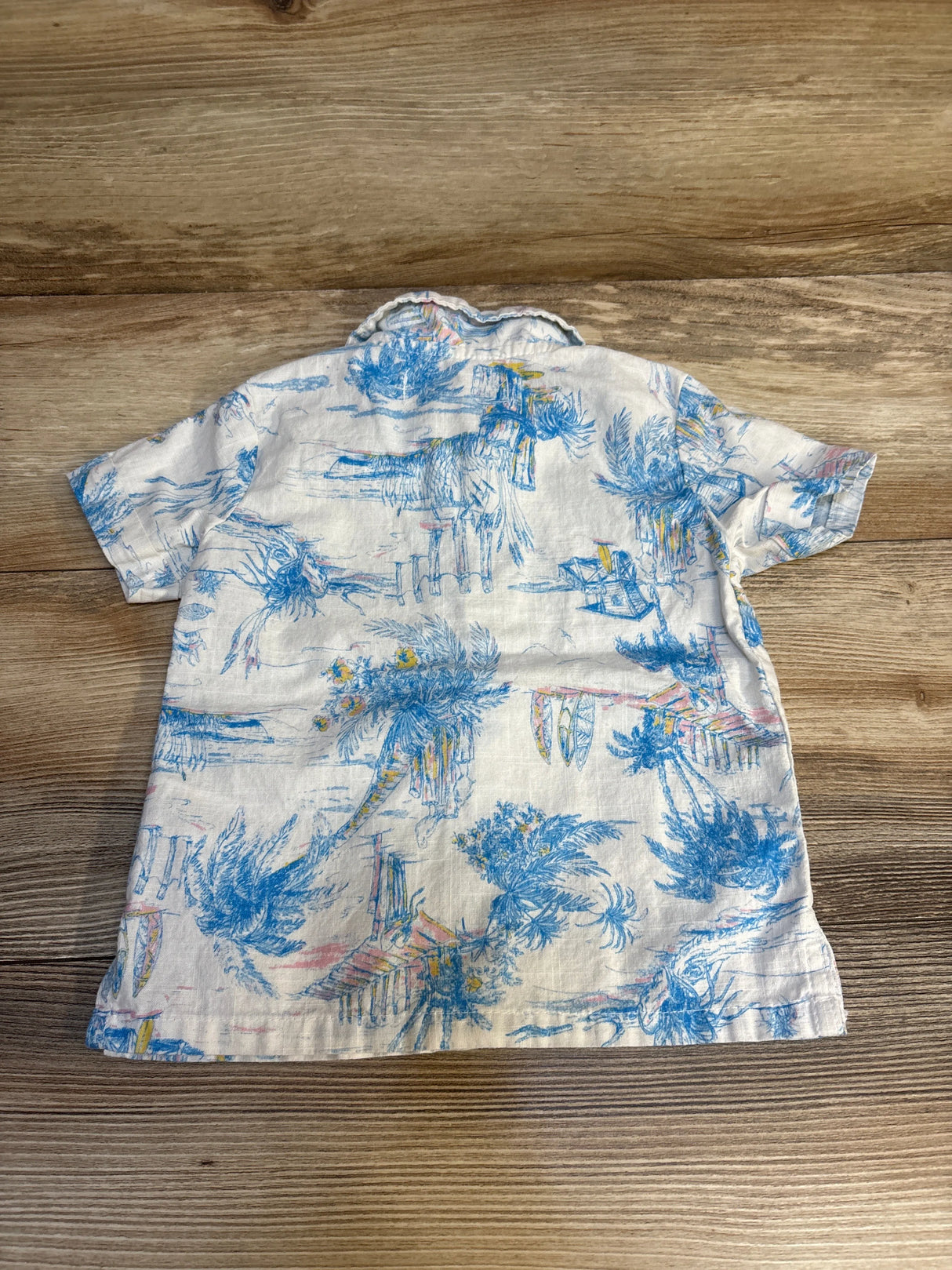 Kids short sleeve button-up shirt with blue tropical palm tree print on light fabric