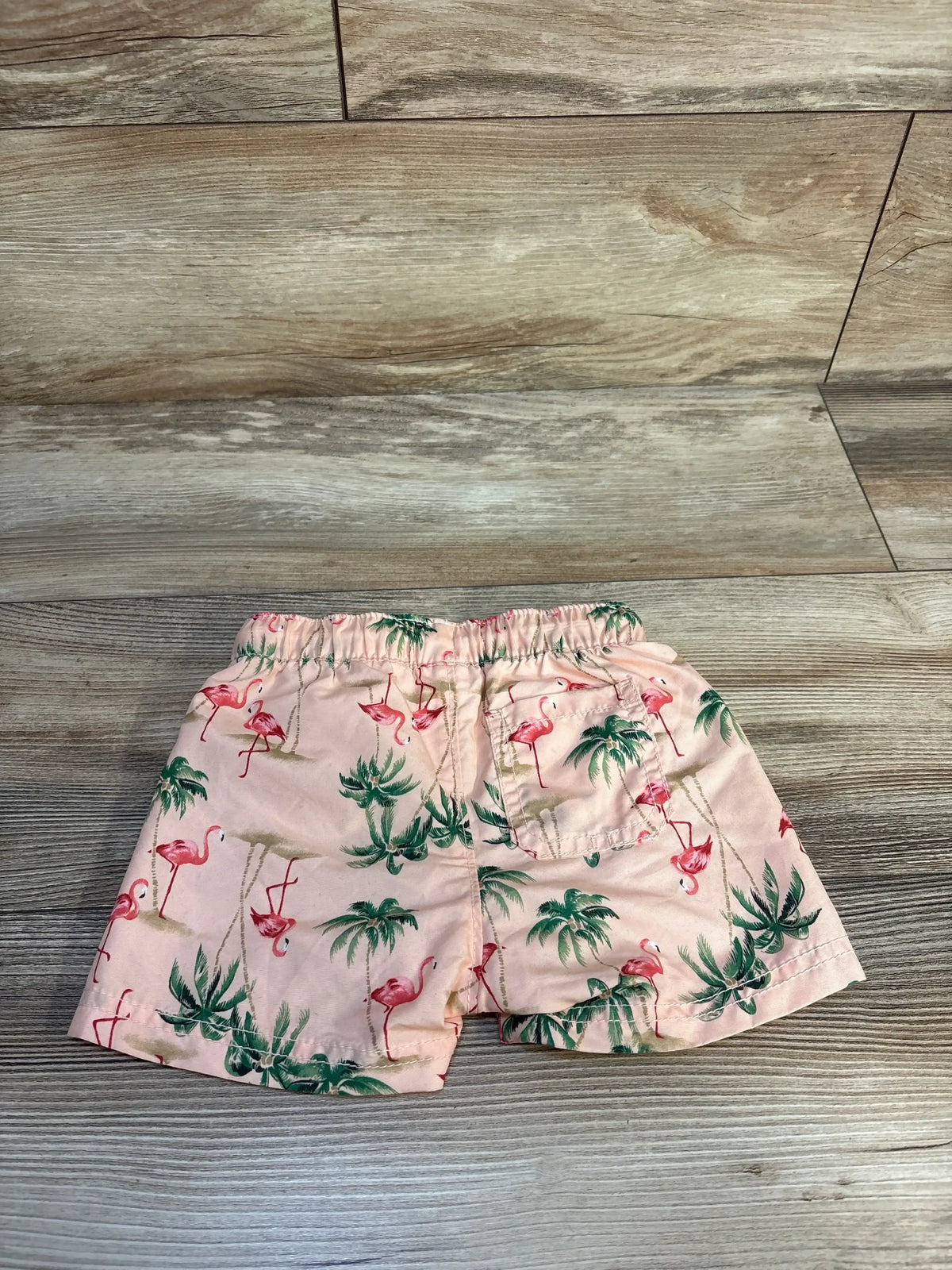 Pink toddler shorts with flamingo and palm tree print on wooden background