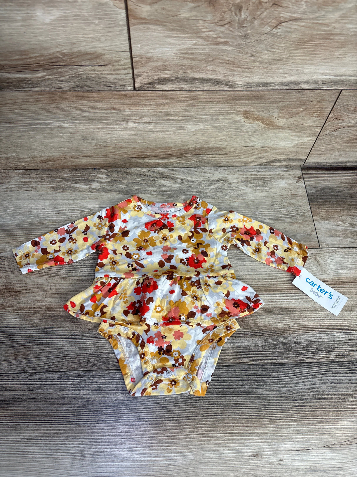 Carter's baby long-sleeve floral printed bodysuit with peplum skirt on wooden floor