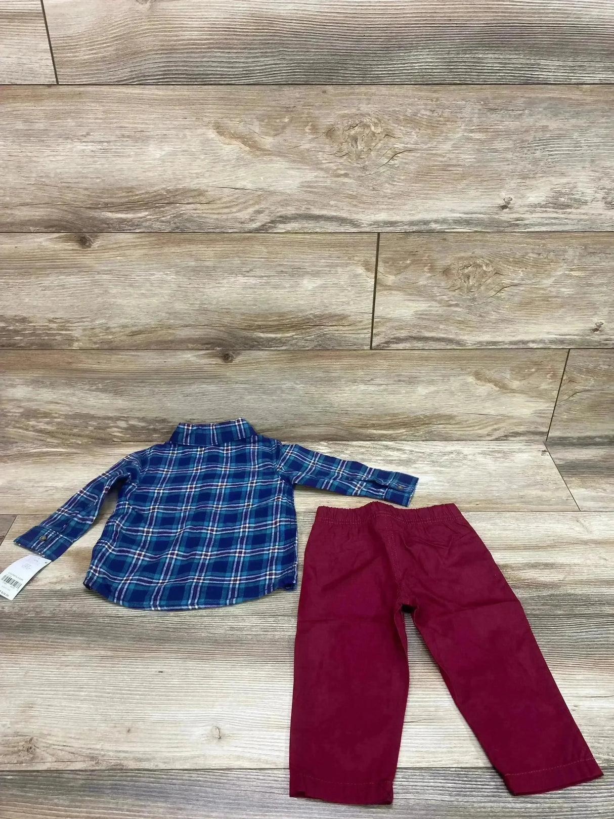 Flat lay of Carter’s 2-piece baby set with blue plaid button-up shirt and red elastic-waist pants on light wood background
