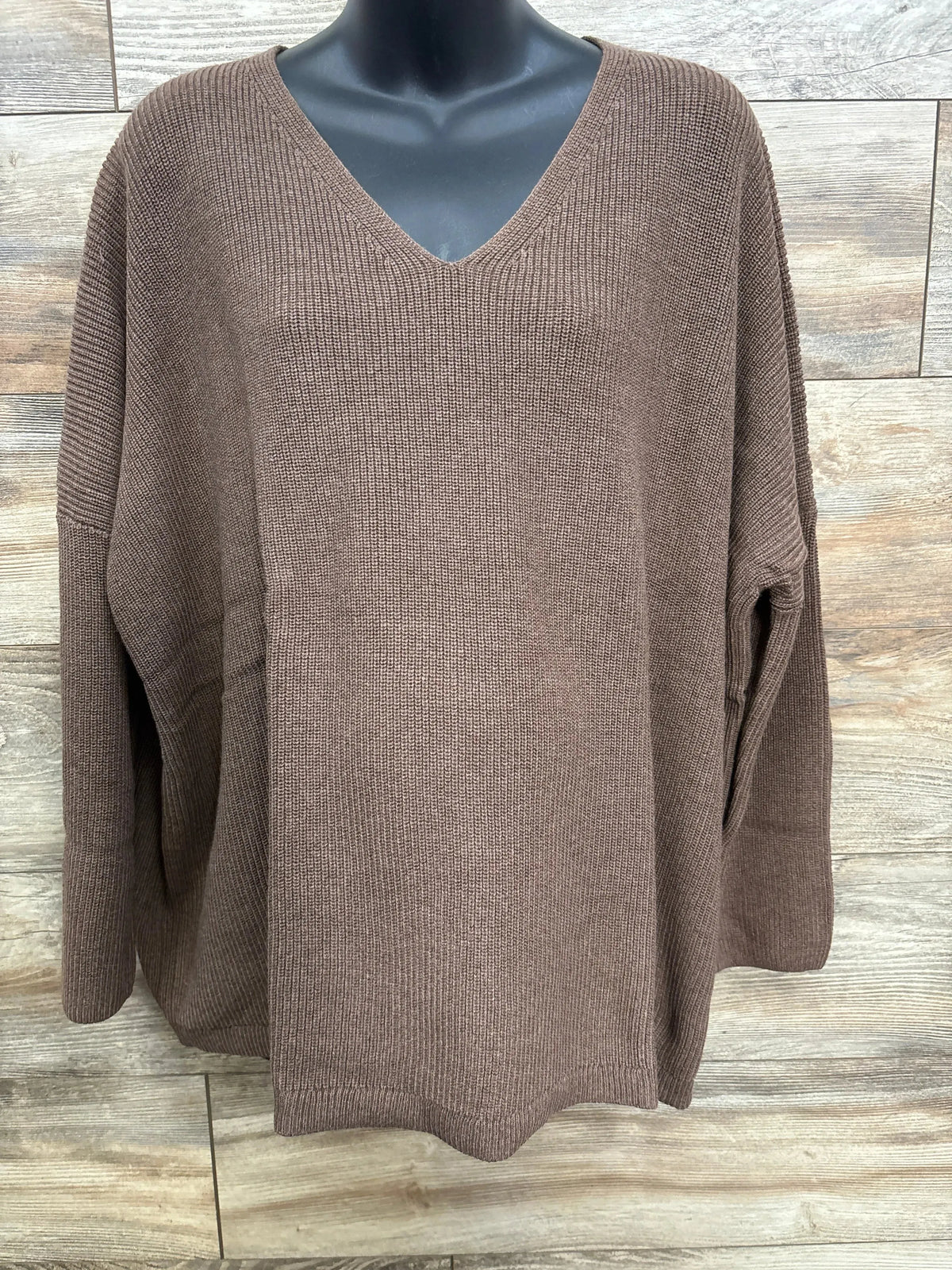 Brown V-neck knit sweater with long sleeves on black mannequin against wood background