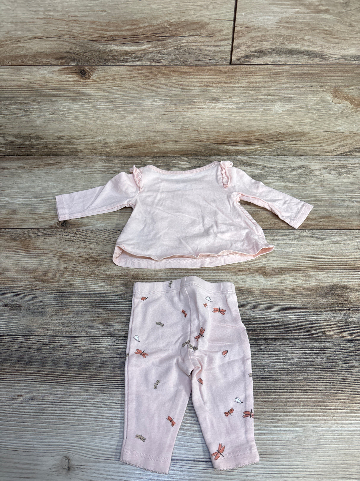 Pink baby outfit set with long sleeve top and dragonfly print pants on wood floor