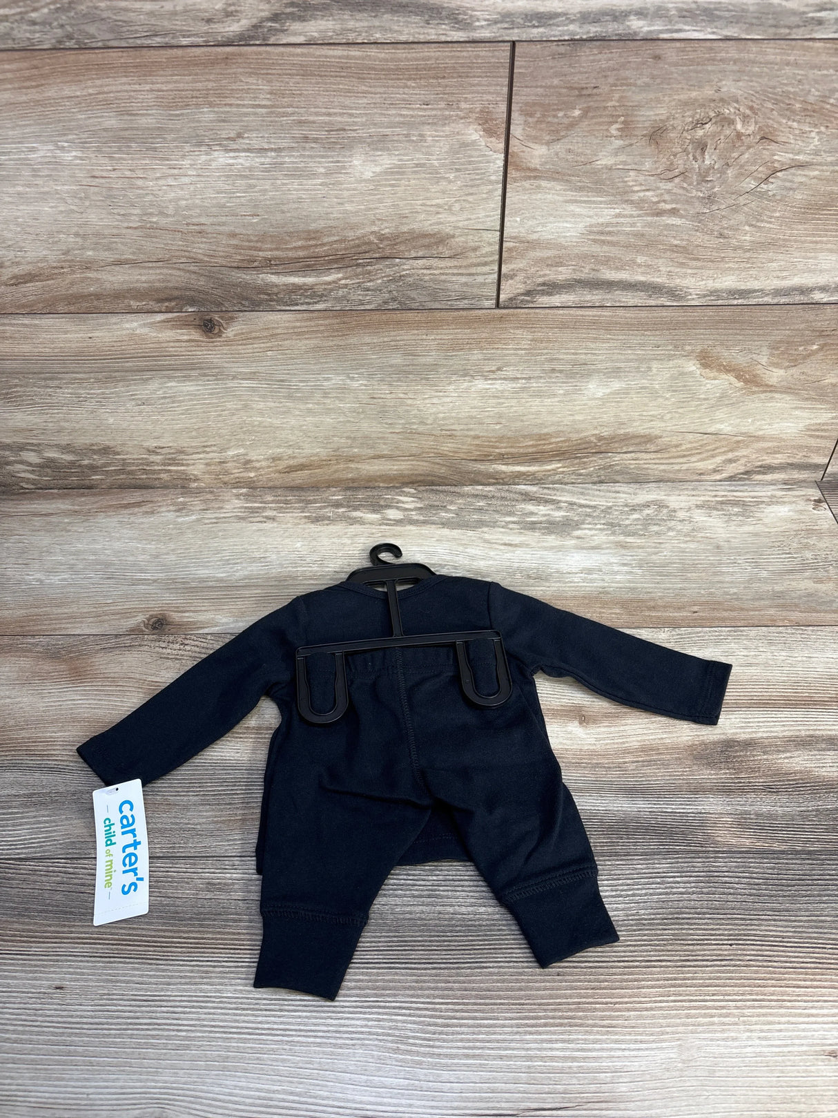 Carter's navy blue baby onesie with tag, laid flat on wood floor for resale