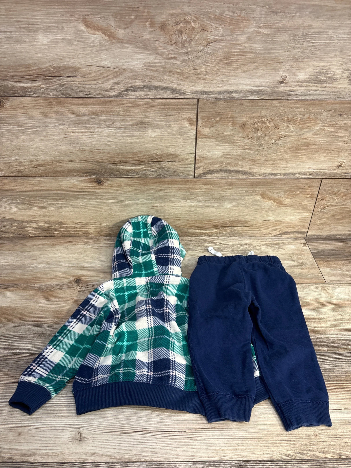 Green plaid hoodie and navy pants set for toddlers on wood background