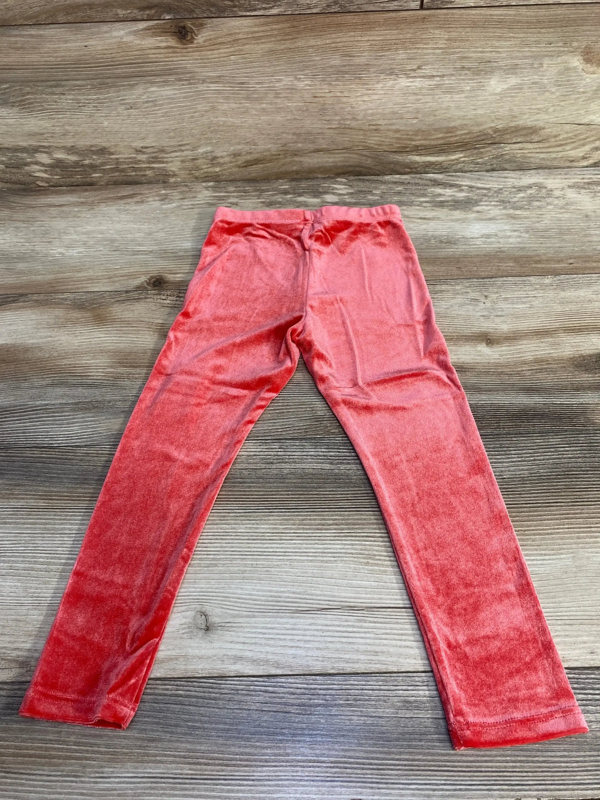 Red velvet kids leggings on wood background, stylish soft children's pants
