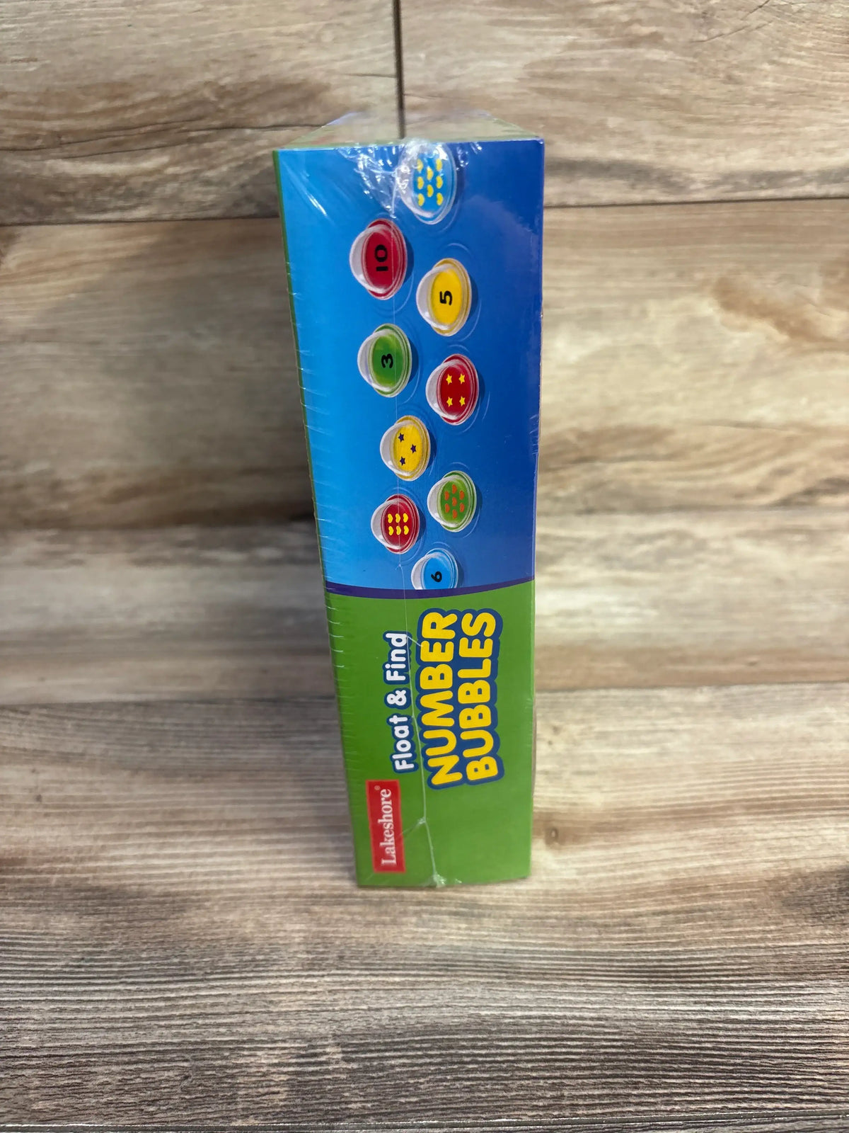Side view of Float and Find Number Bubbles box showing numbered floating pieces on a wood surface