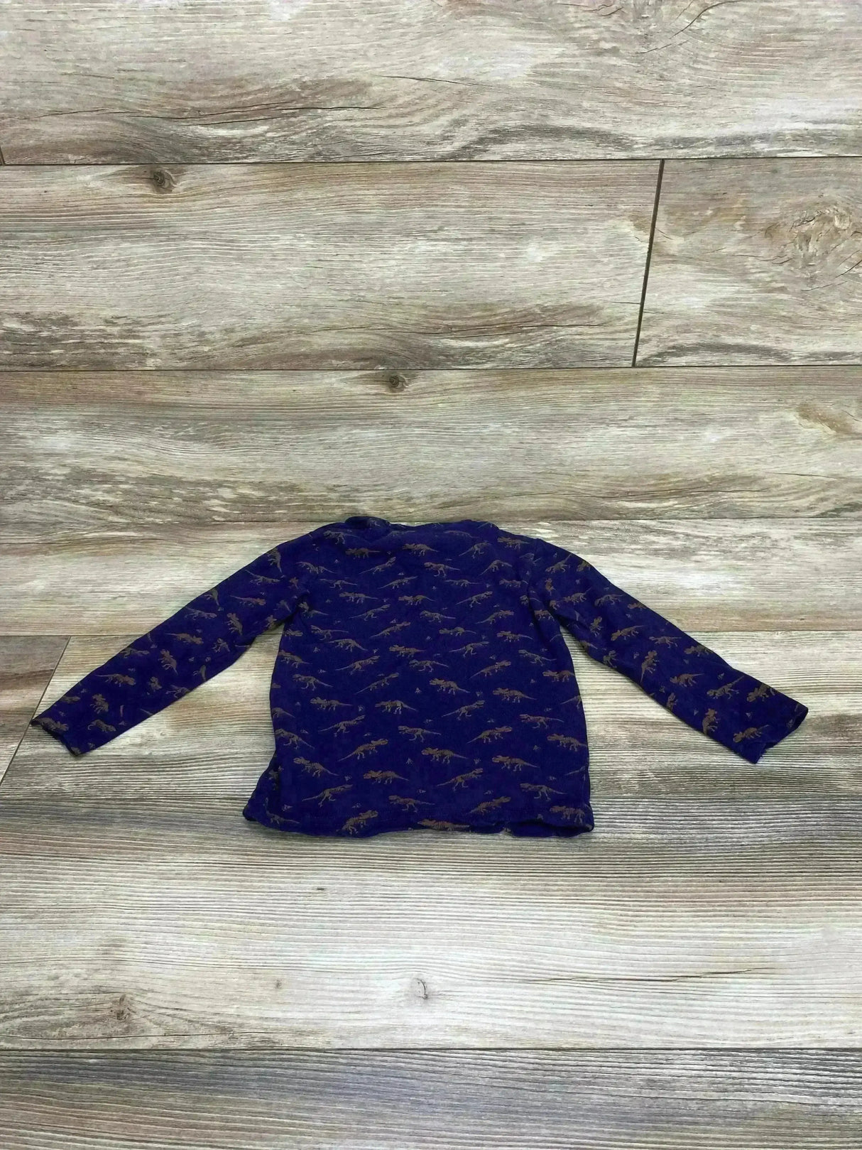 Flat-lay back view of navy dino long-sleeve toddler shirt (size 4T) showcasing brown all-over dinosaur print on light wood background