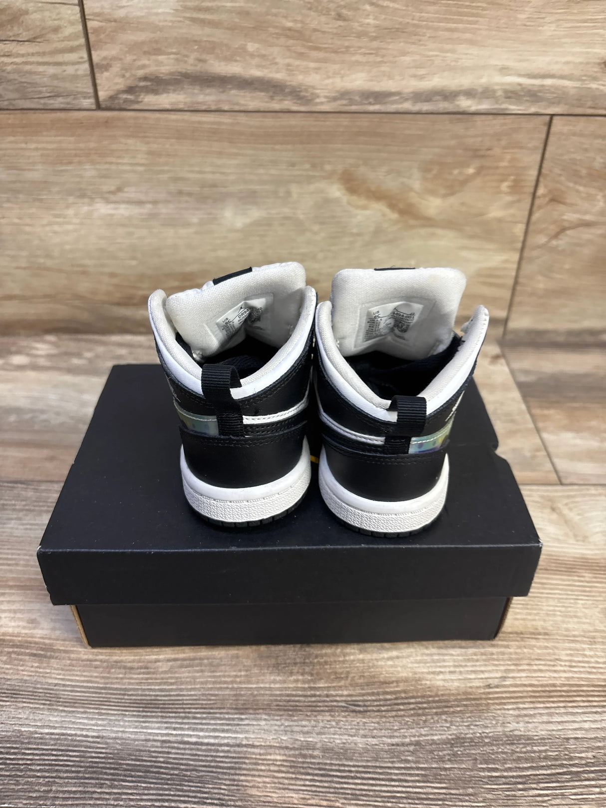 Rear view of Jordan 1 Mid Hologram toddler sneakers showing holographic heel tab and white midsoles on a black shoebox