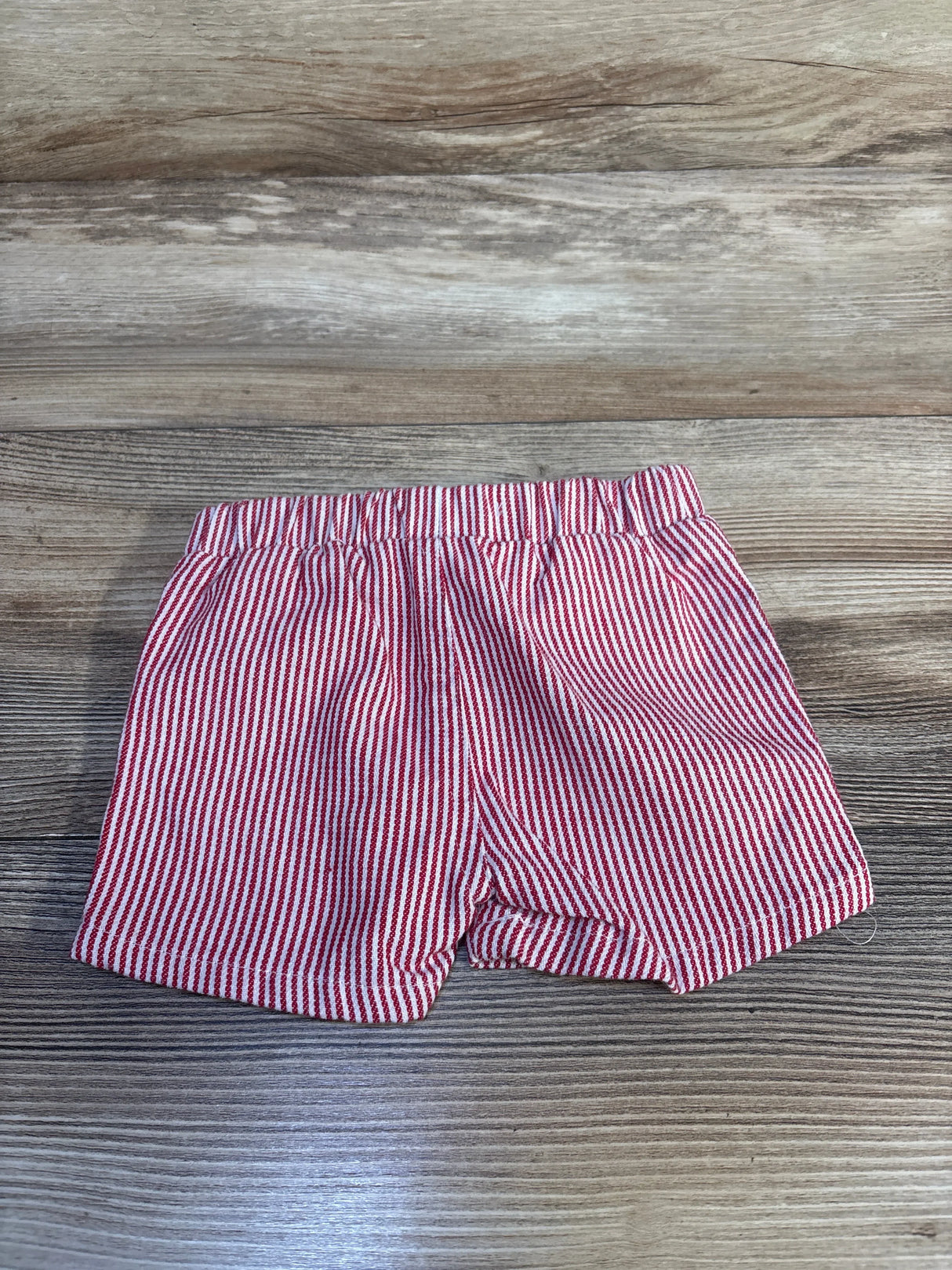 Red and white striped baby shorts on wood floor, kids clothing resale