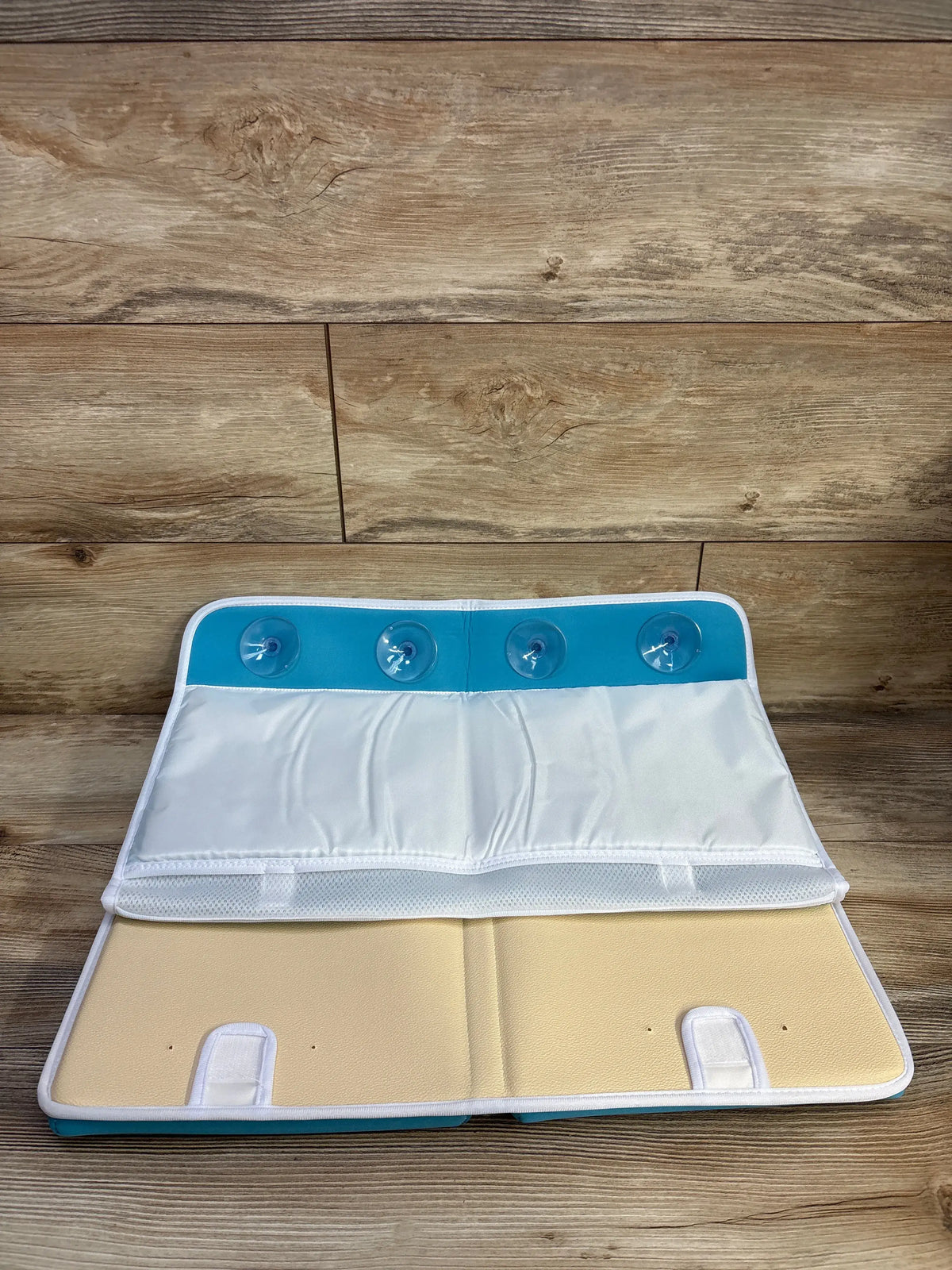Front view of Gamexcel baby bath kneeler and elbow rest showcasing four suction cups and storage pockets on a wood floor