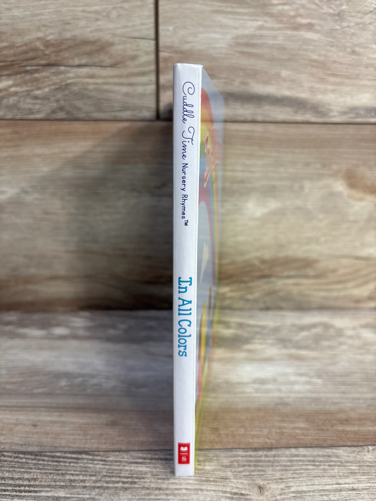 Cuddle Time Nursery Rhymes In All Colors children's book spine on wood background