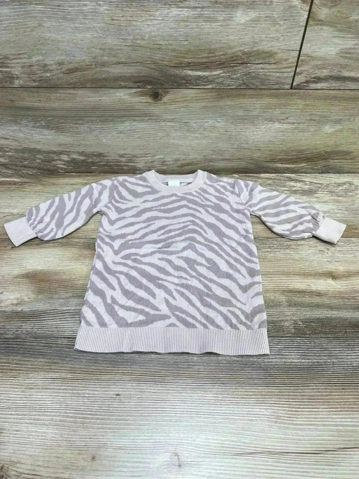 Flat lay of Baby Gap tiger-stripe sweater dress 12-18m, light pink and cream pattern with puff sleeves on wood background