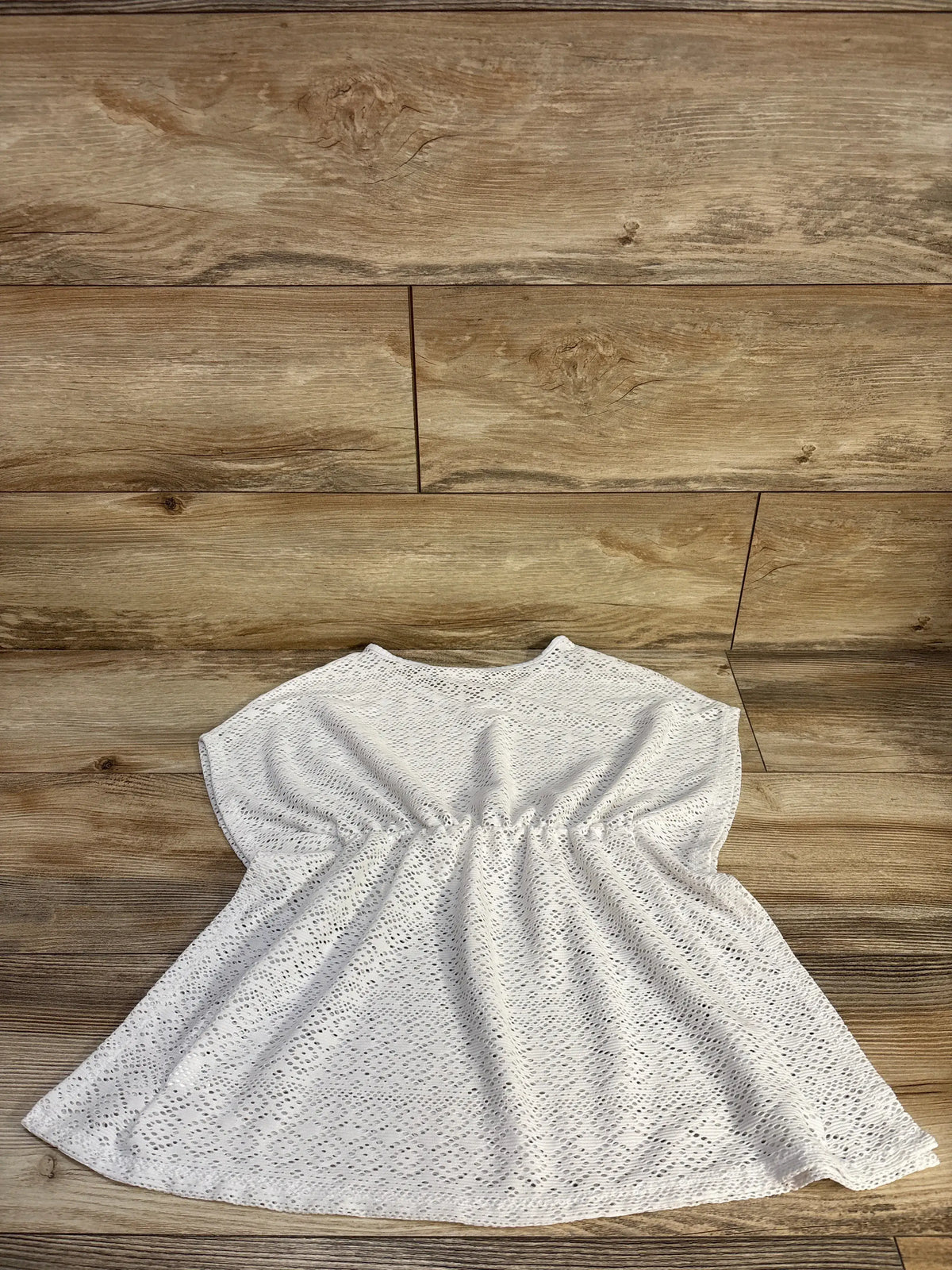 Front view of Children’s Place white short sleeve lace swim cover-up showcasing shirred waist with a wood plank background